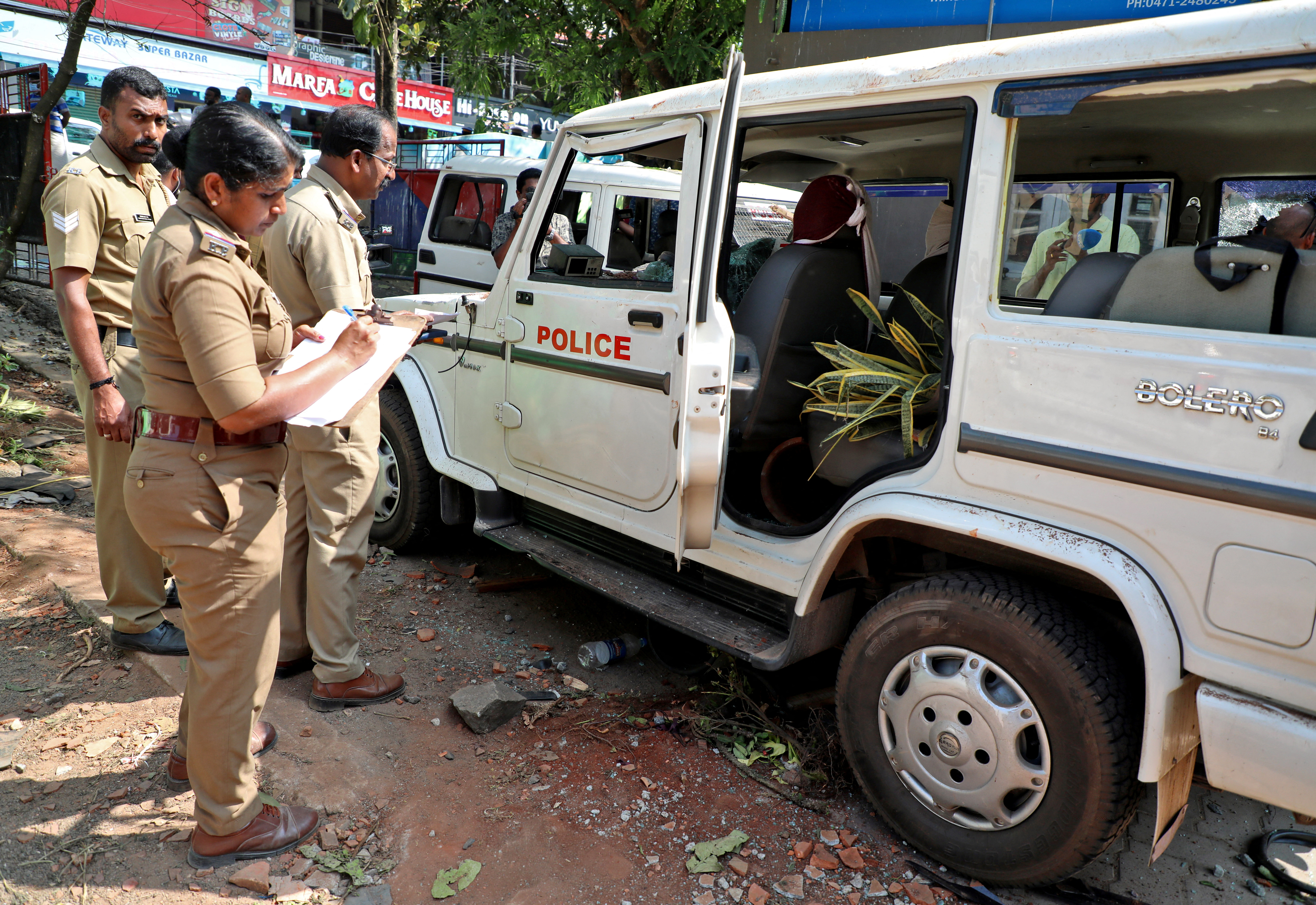 Police officers examine a vehicle that was damaged during a clash with protesters at a police station near the proposed Vizhinjam Port