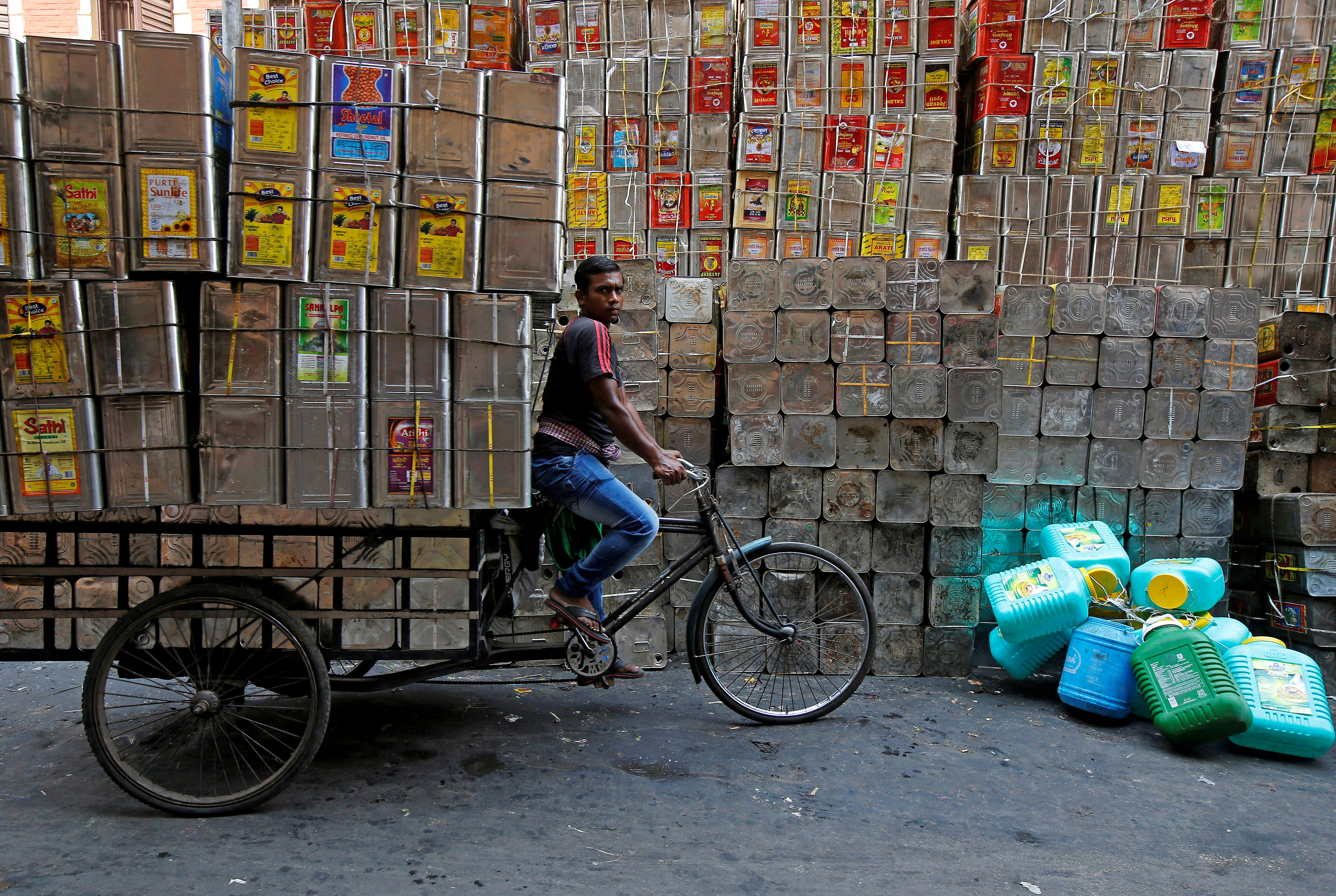 A man pedals a tricycle loaded with empty cooking oil containers in Kolkata