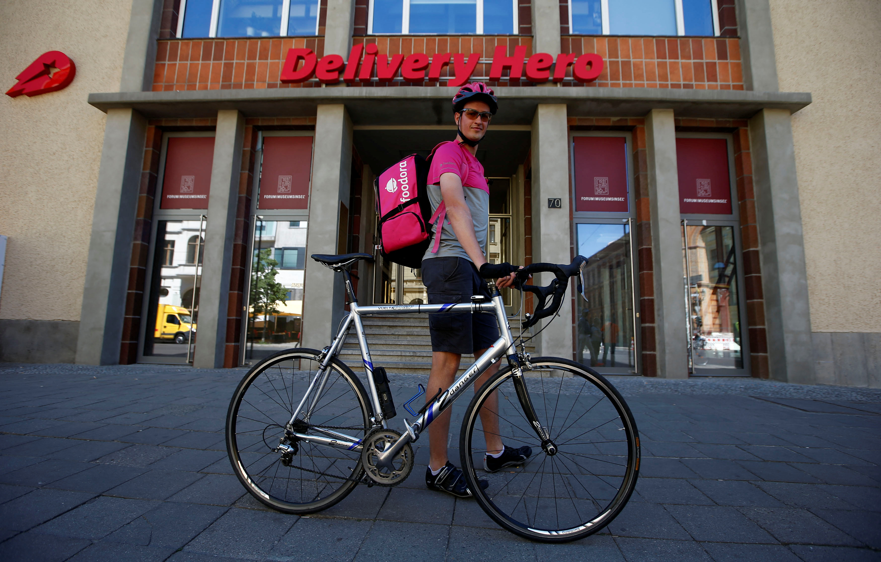A Foodora delivery cyclist poses in front of the Delivery Hero headquarters in Berlin, Germany, June 2, 2017. REUTERS/Fabrizio Bensch