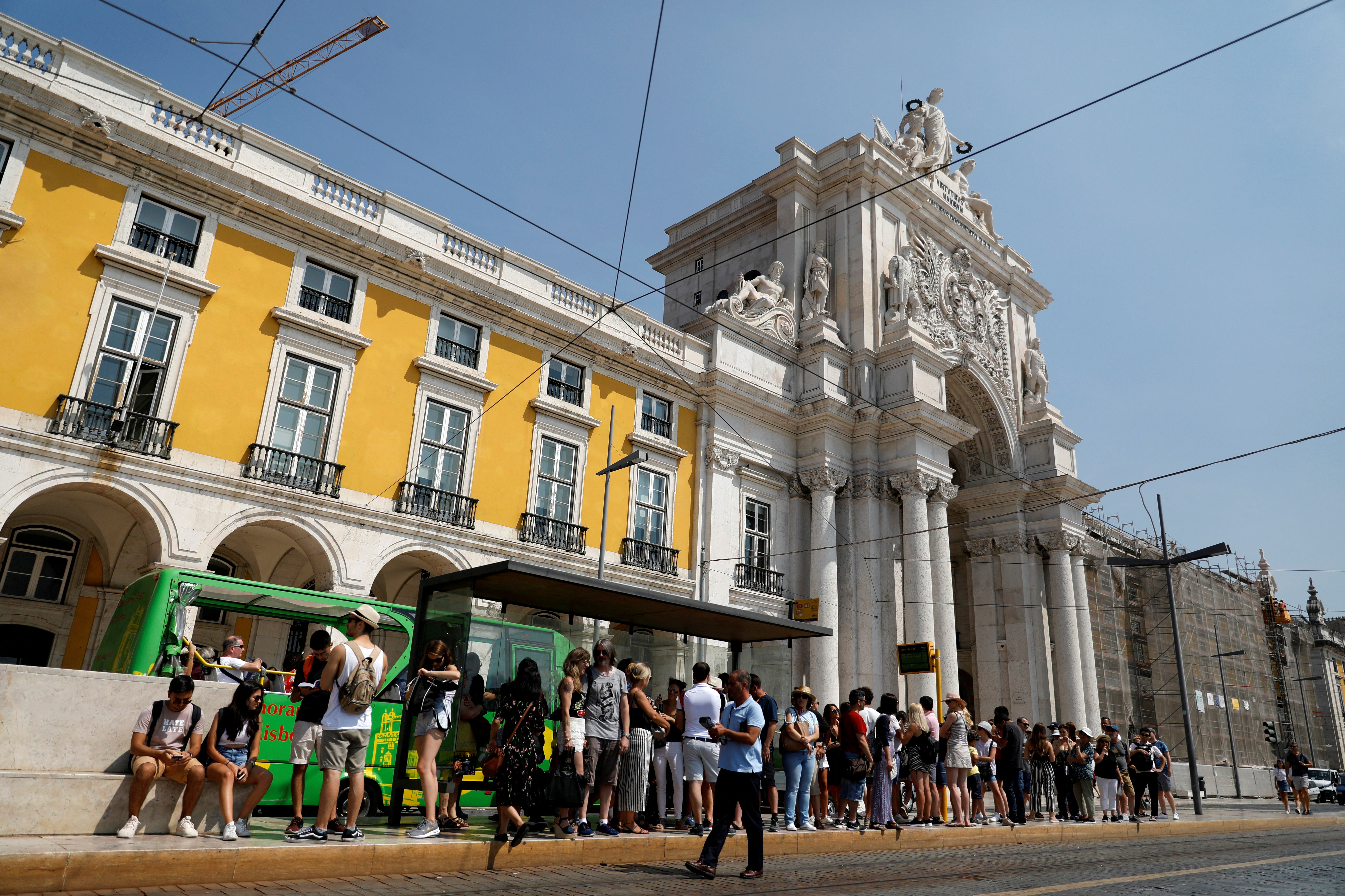 Tourists wait for a tram at Comercio square in downtown Lisbon