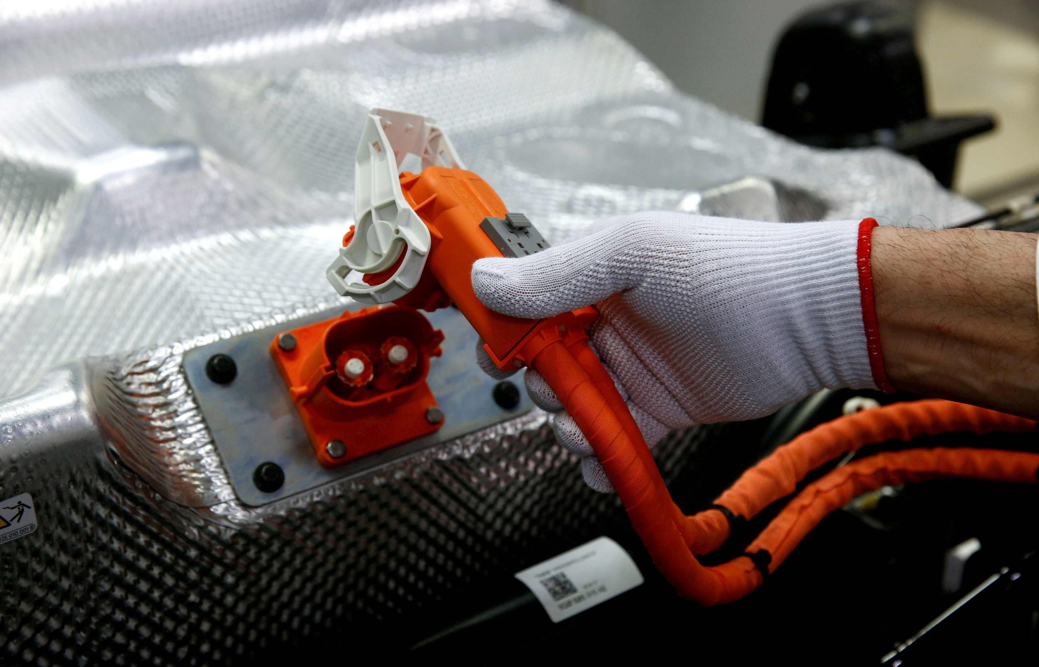 Worker connects the battery during the assembly of a VW e-Golf electric car at the Transparent Factory in Dresden