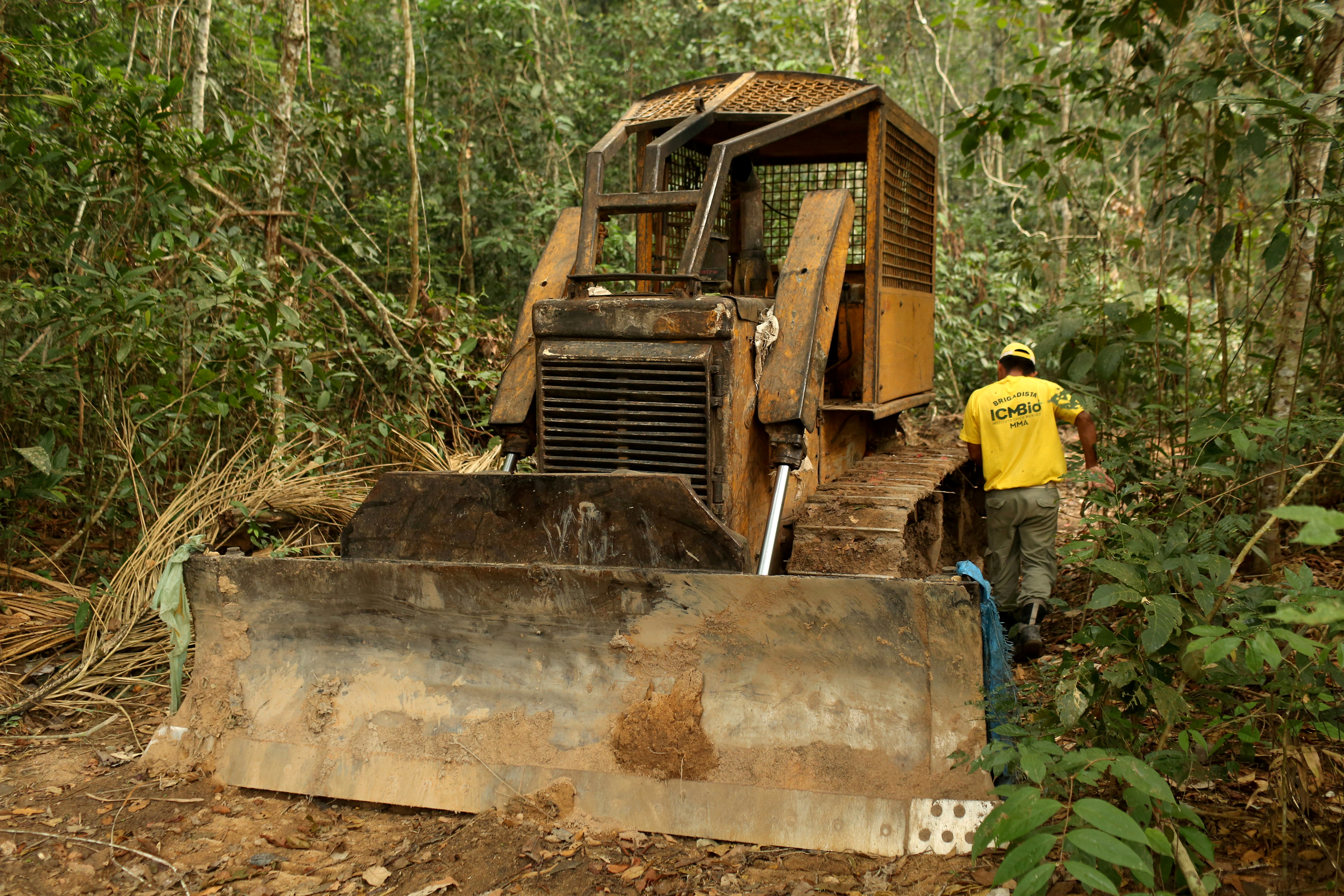 A member of the Chico Mendes Institute for Biodiversity Conservation (ICMBio) walks next a tractor used for deforestation at the National Forest Bom Futuro in Rio Pardo