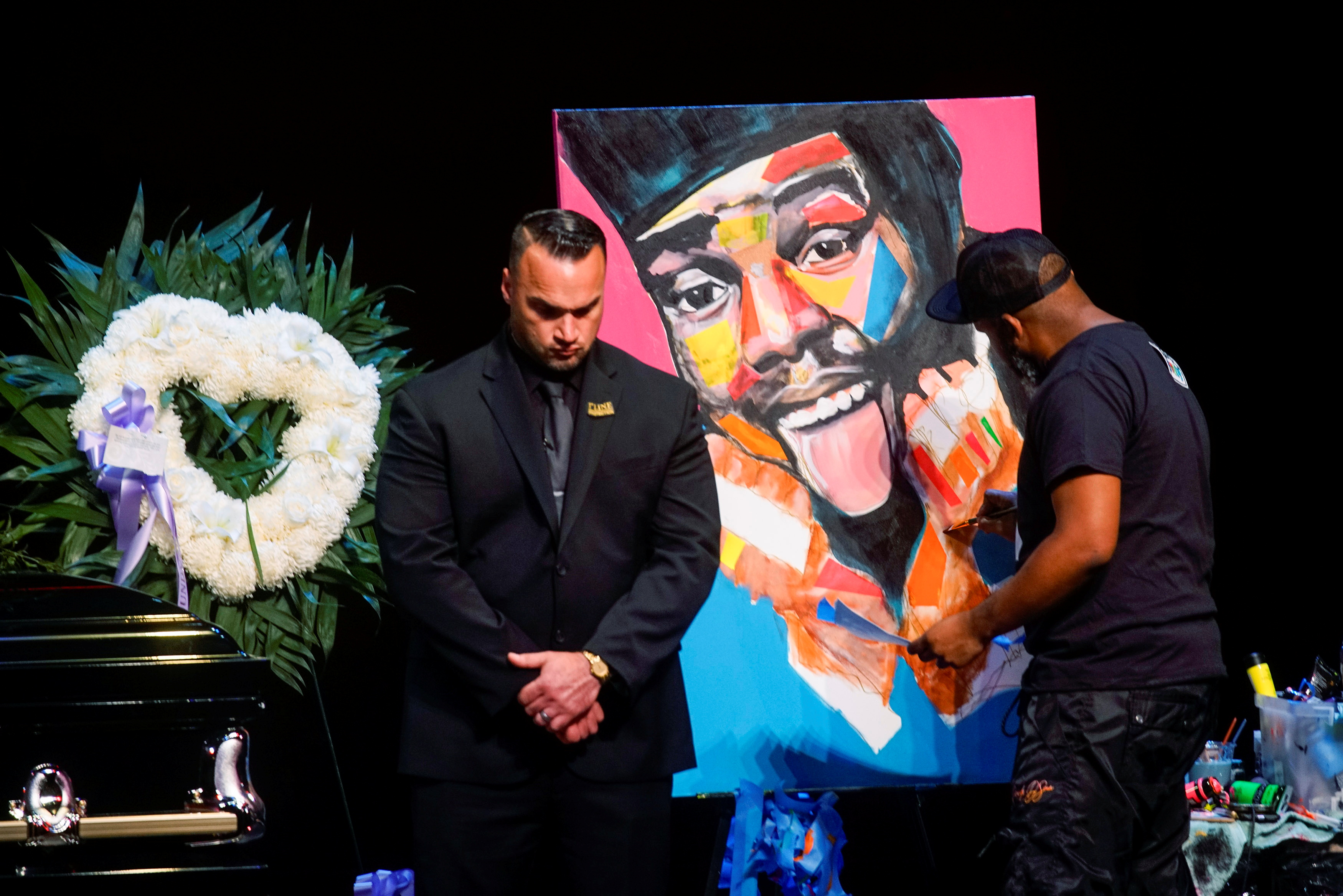 An artist paints a portrait for late rapper Marcel Theo Hall, known by his stage name Biz Markie, next to his casket during the funeral service in Patchogue