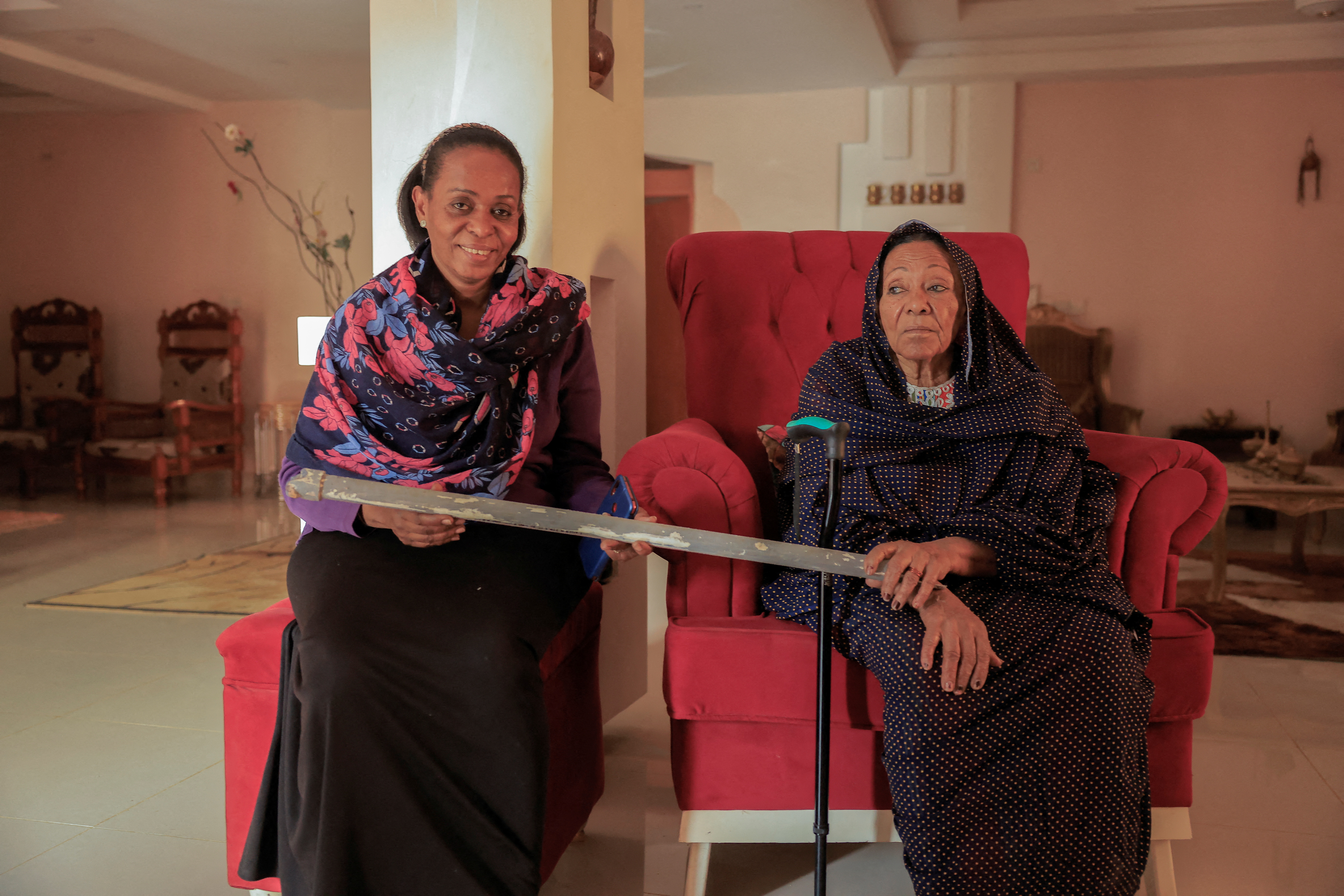 Mother and sister of prominent Sudanese women's rights campaigner Amira Osman carry a stick left by security after arrest in her home in Khartoum