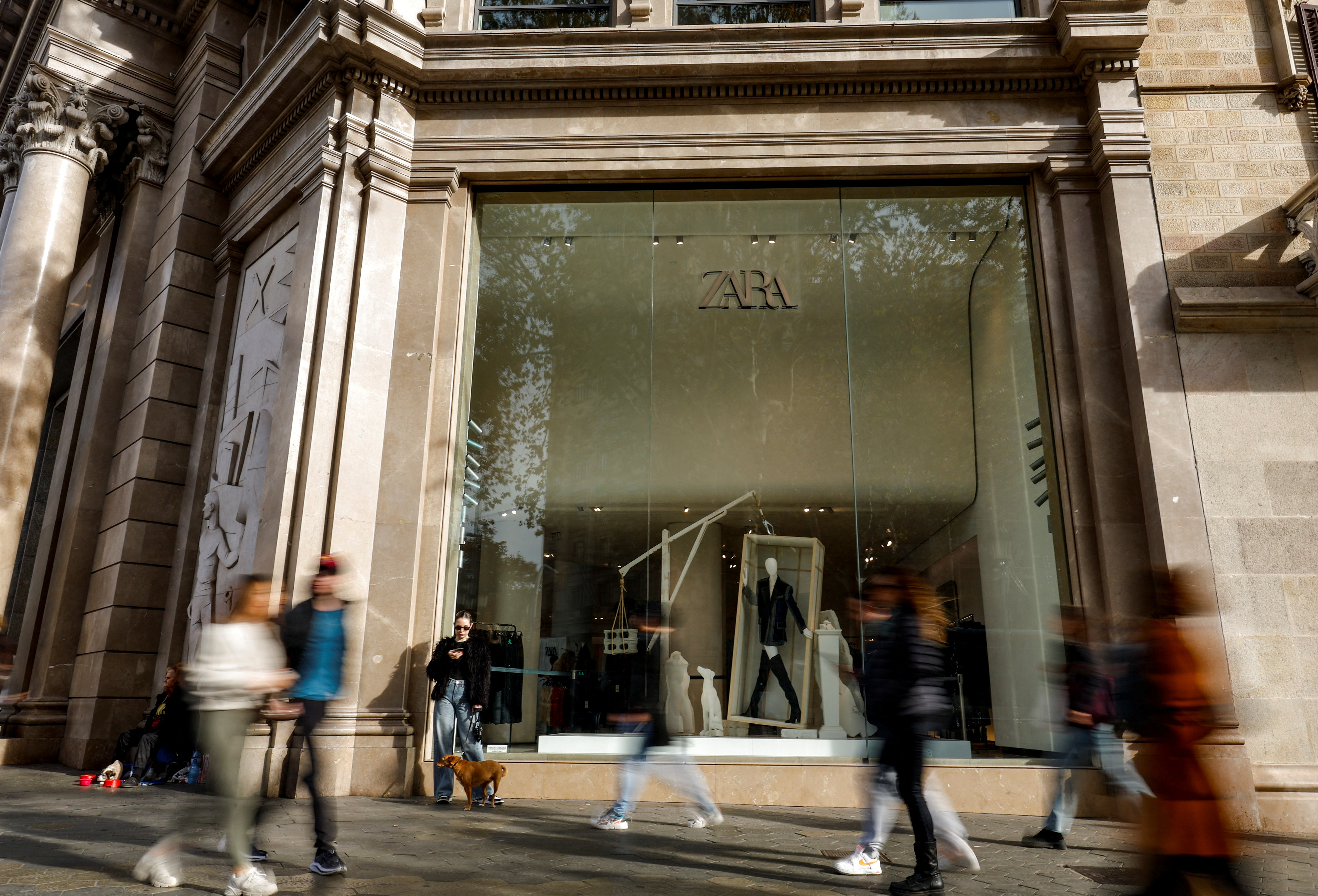 People walk past a Zara shop window at Passeig de Gracia in Barcelona