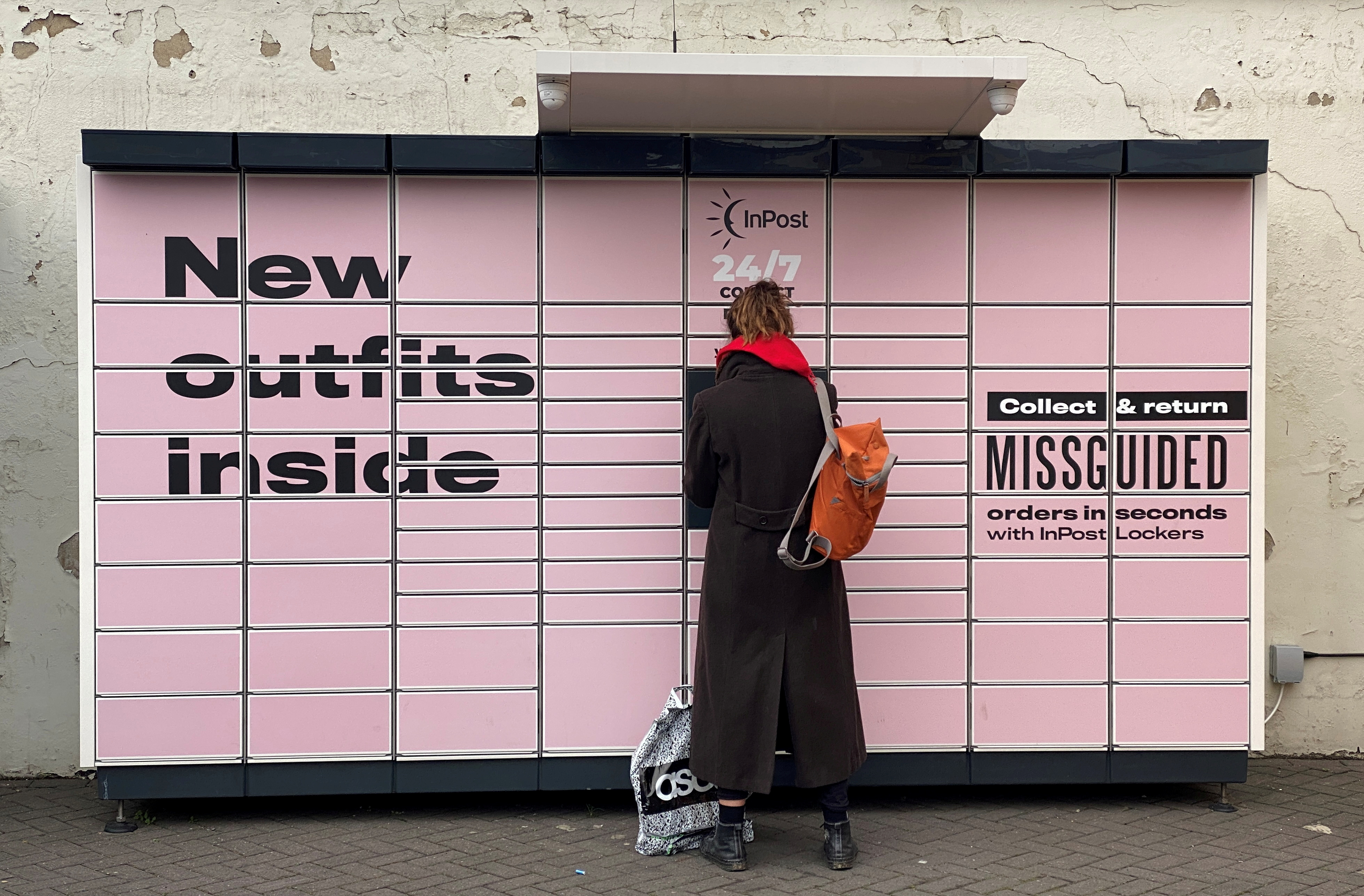 A woman stands at an InPost locker in Hackney, London