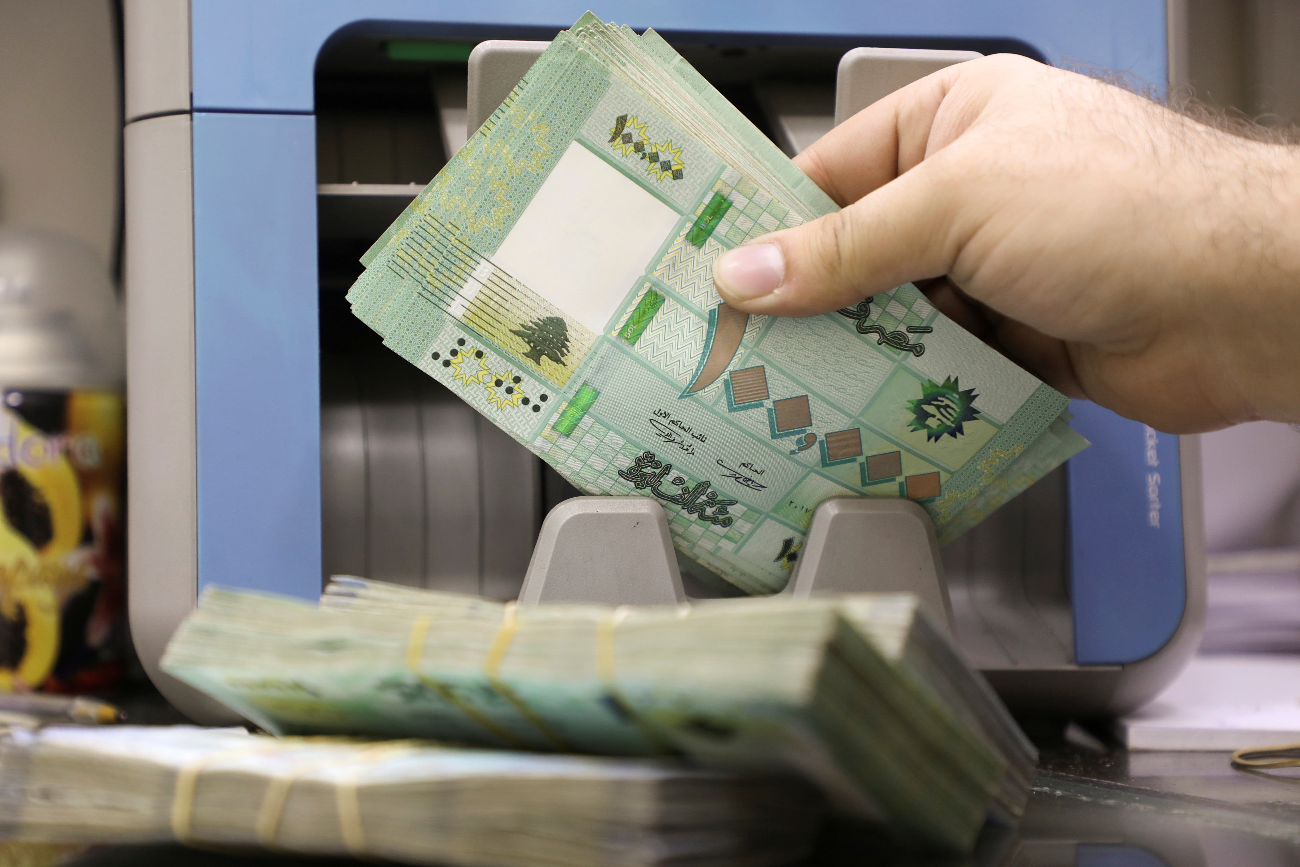 A man counts Lebanese pound banknotes at a currency exchange shop in Beirut