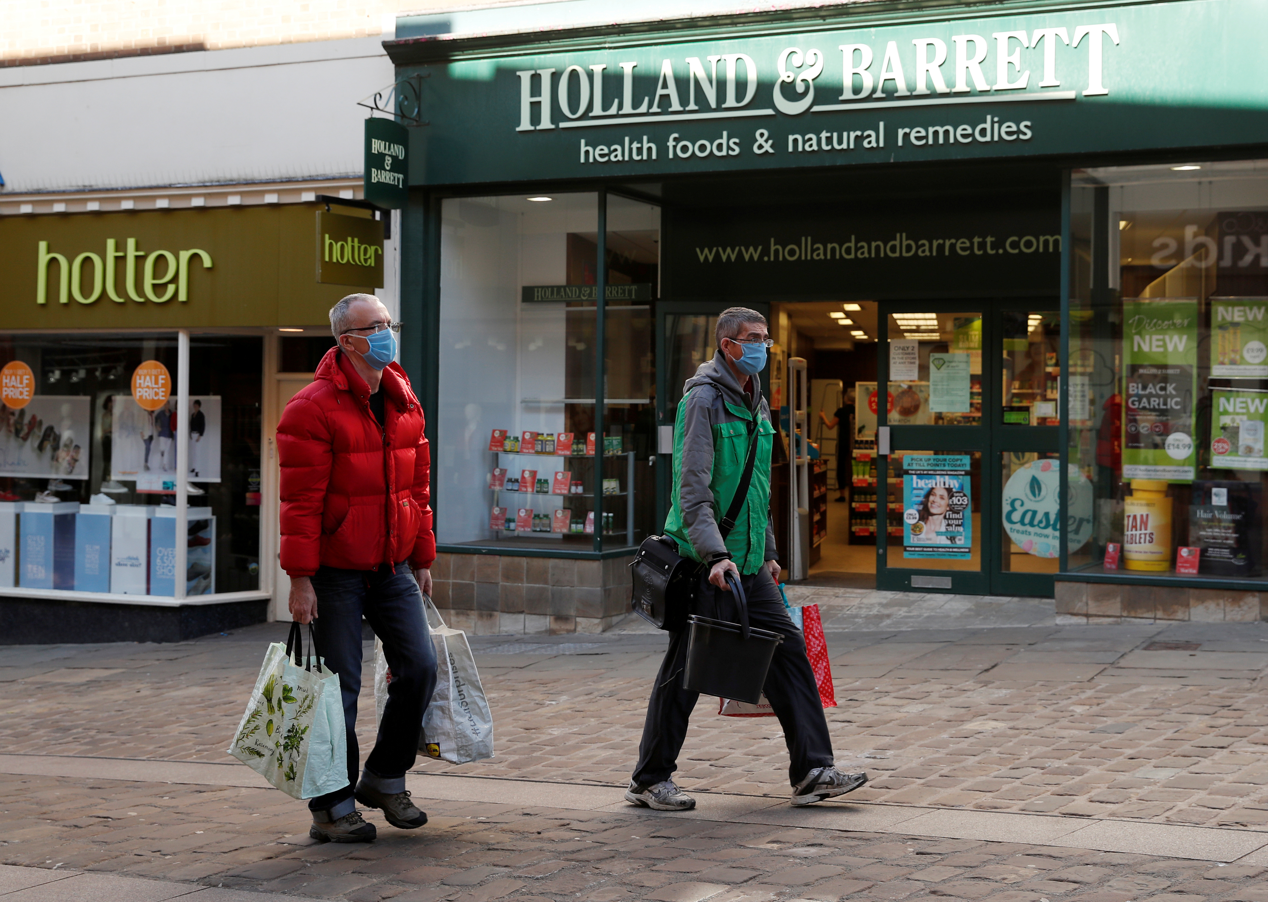 People wearing protective face masks are seen outside a Holland & Barrett store in Durham, as the spread of the coronavirus disease (COVID-19) continues, Durham, Britain
