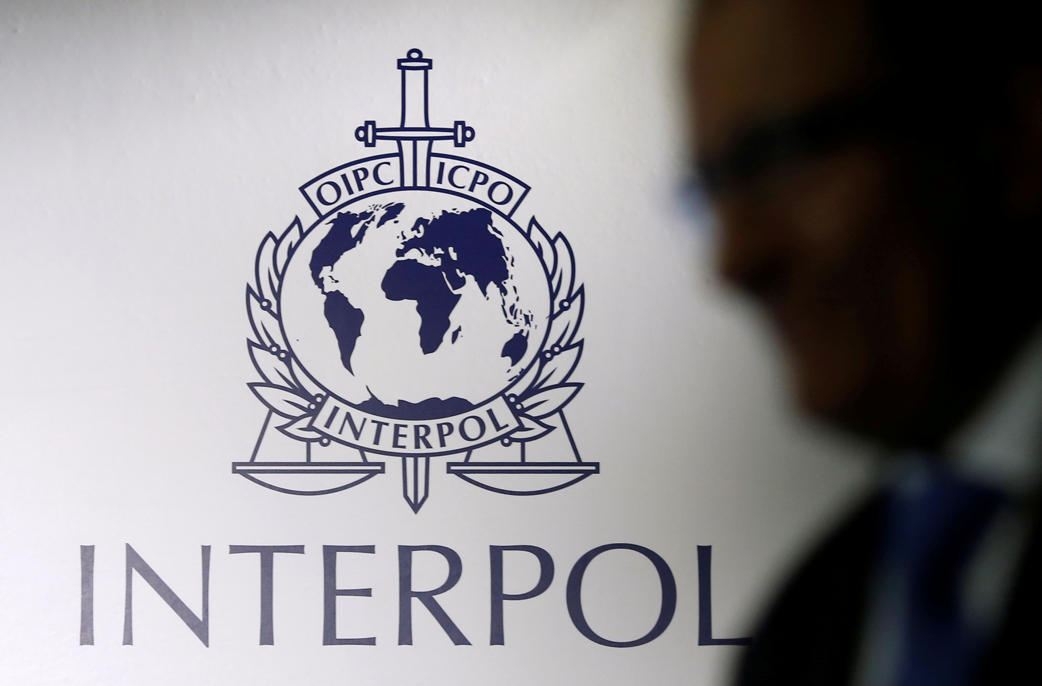A man passes an Interpol logo during the handing over ceremony of the new premises for Interpol's Global Complex for Innovation in Singapore