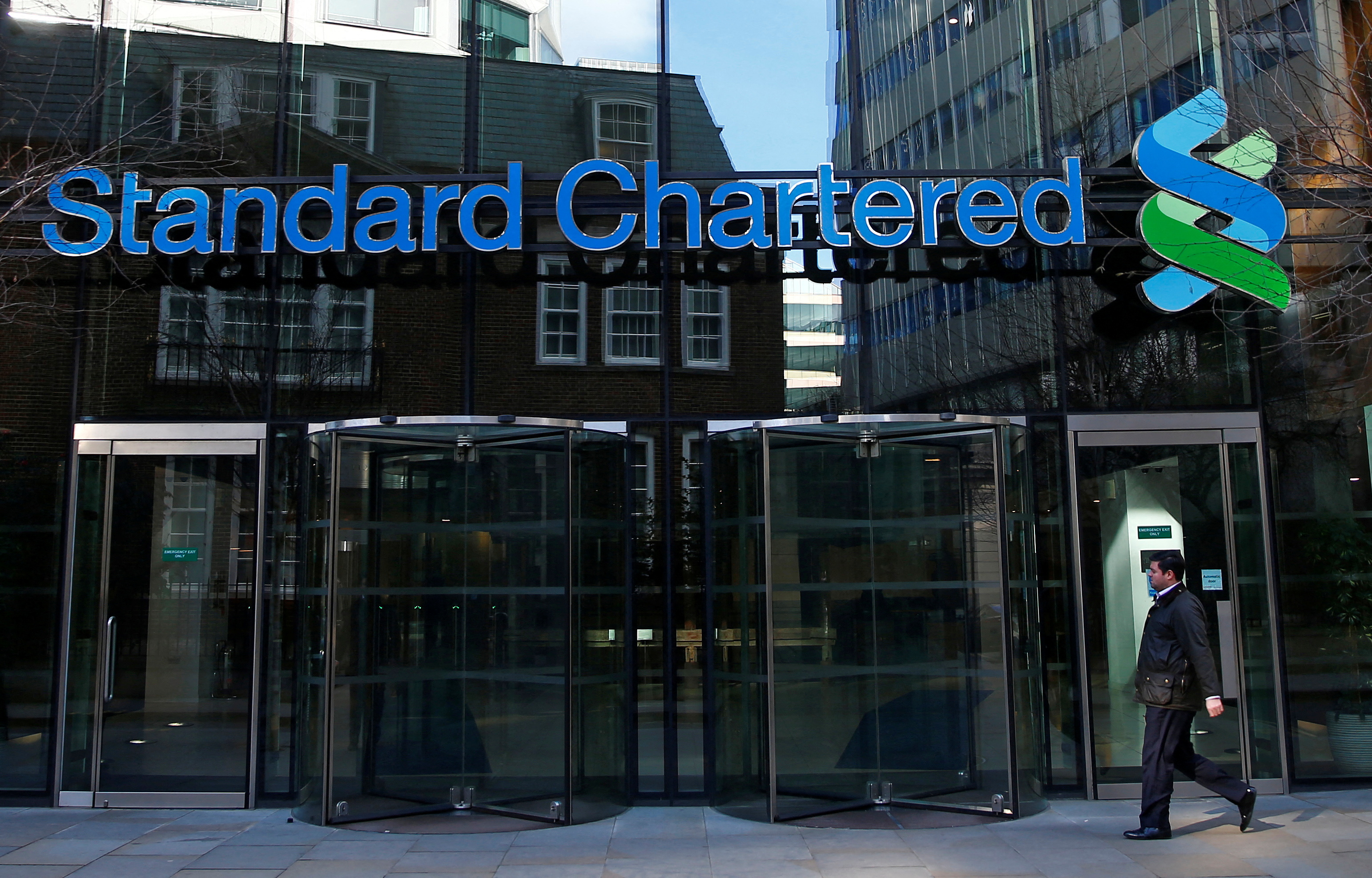 A man walks past the head office of Standard Chartered bank in the City of London