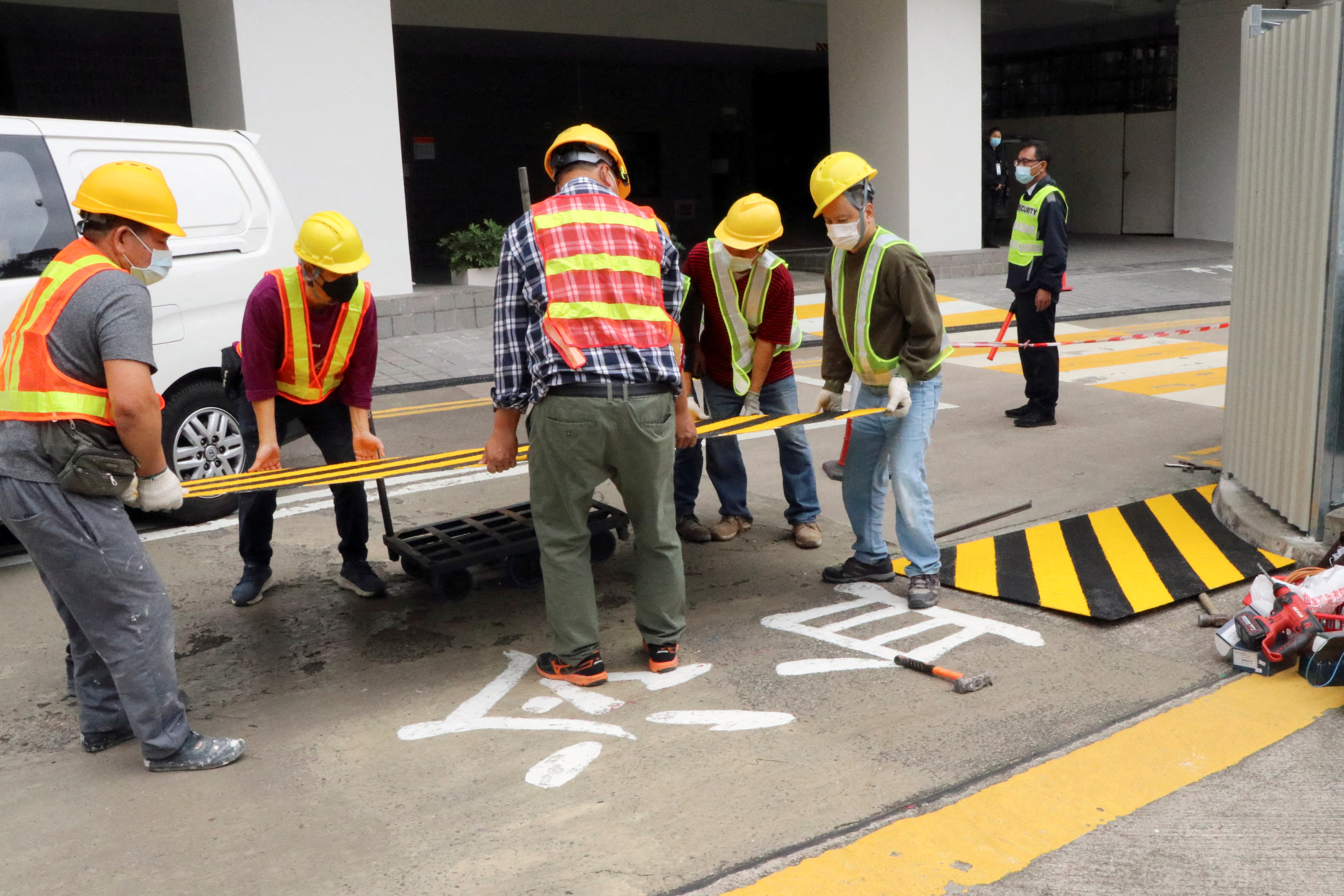 Construction workers cover parts of a painted slogan commemorating the 1989 Tiananmen Square crackdown, in Hong Kong