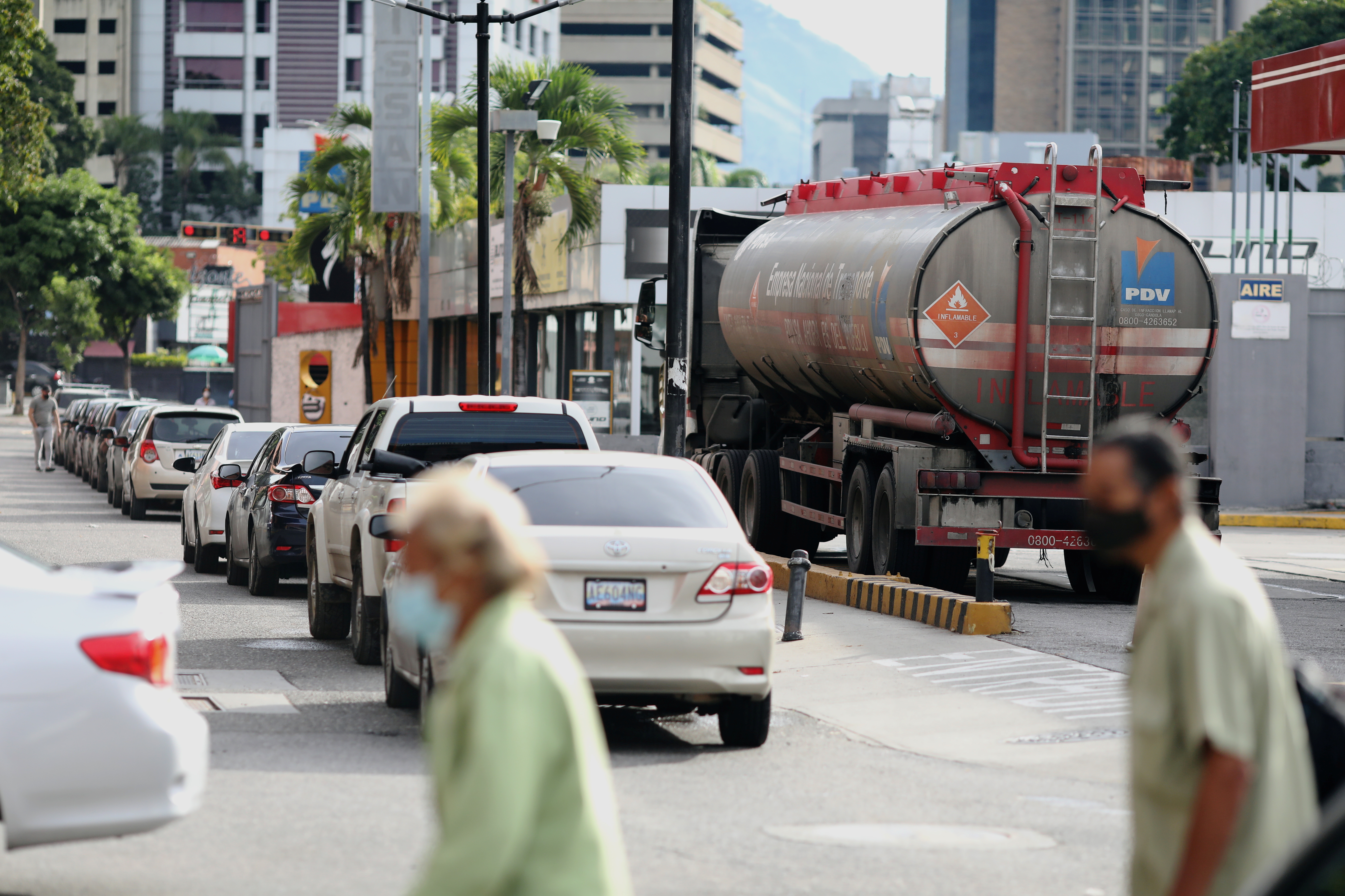 A gas truck is seen next to a line of cars in front of a gas station in Caracas