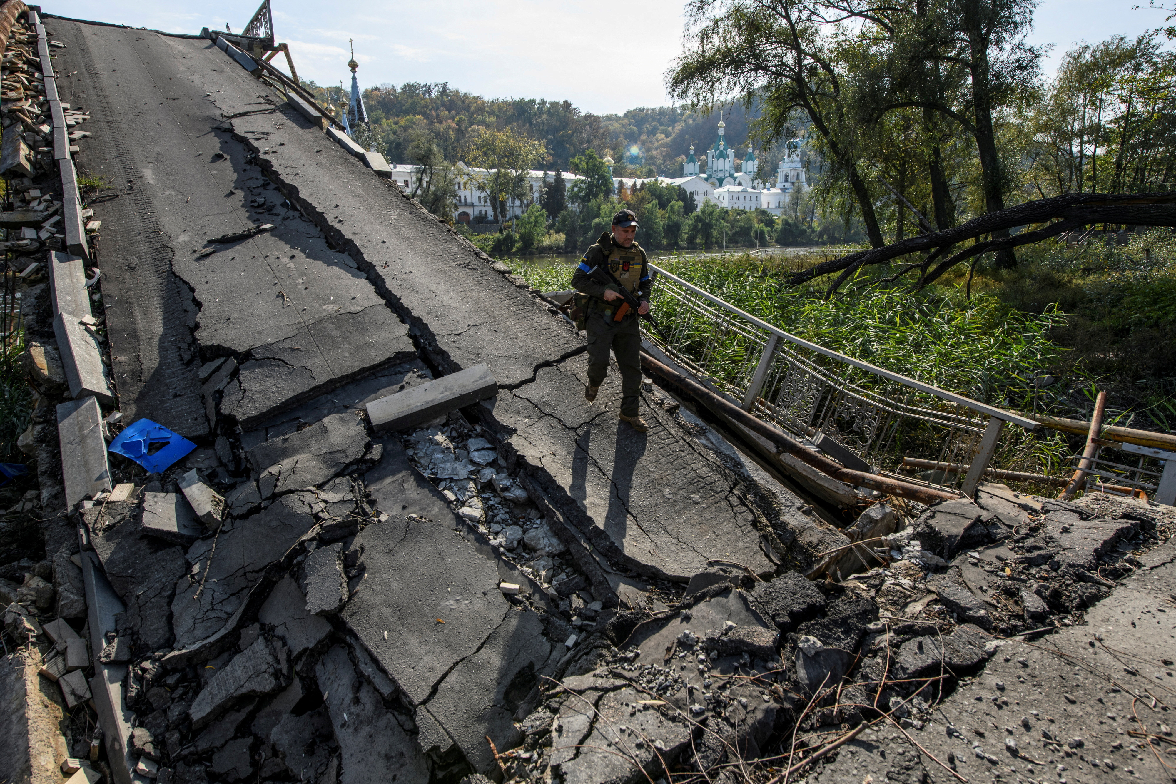 Service member of Ukraine's National Guard walks on a destroyed bridge over the Siverskyi Donets river in the town of Sviatohirsk