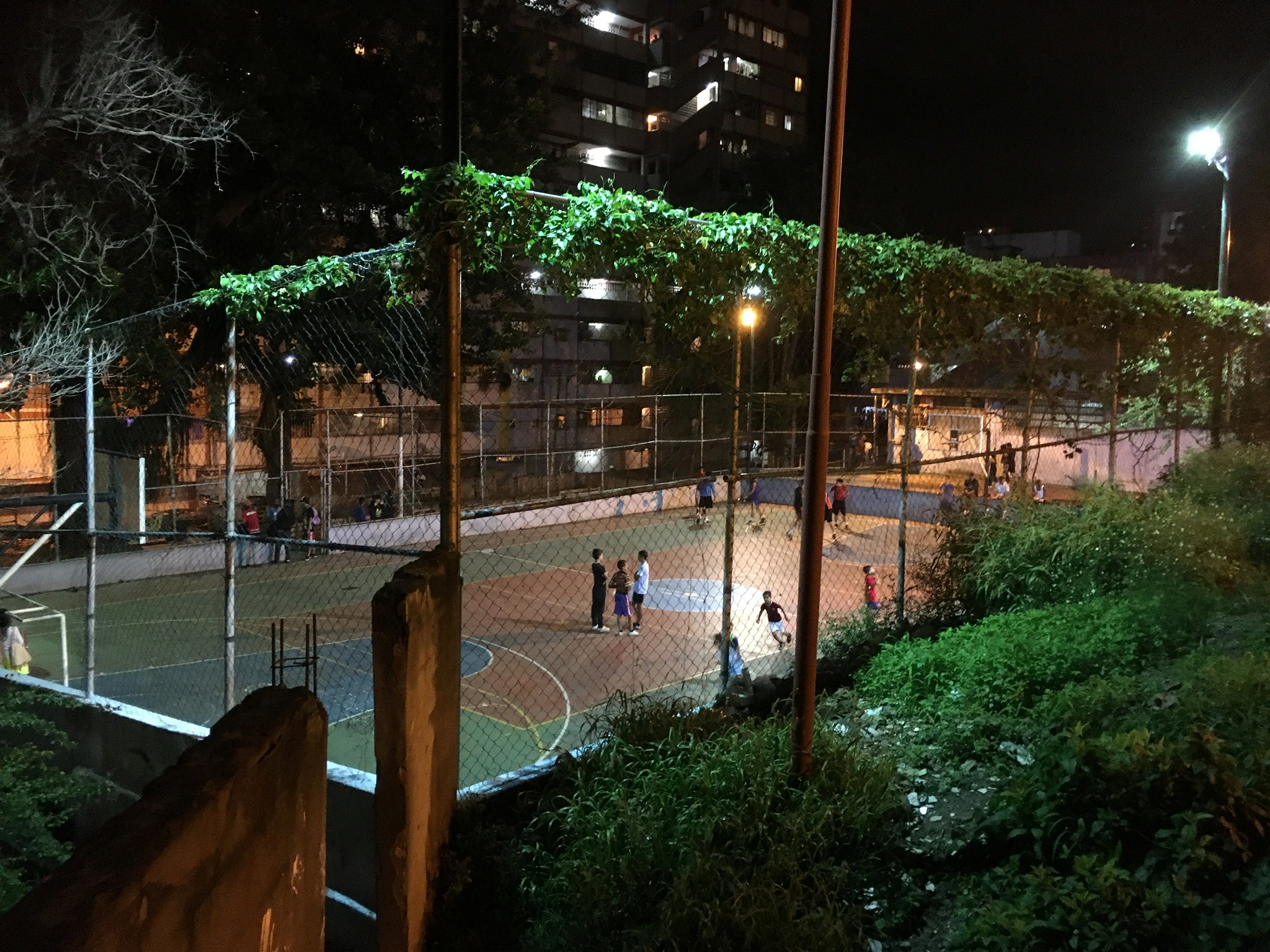Children play football at a multipurpose court under the floodlights in the Artigas neighbourhood in Caracas