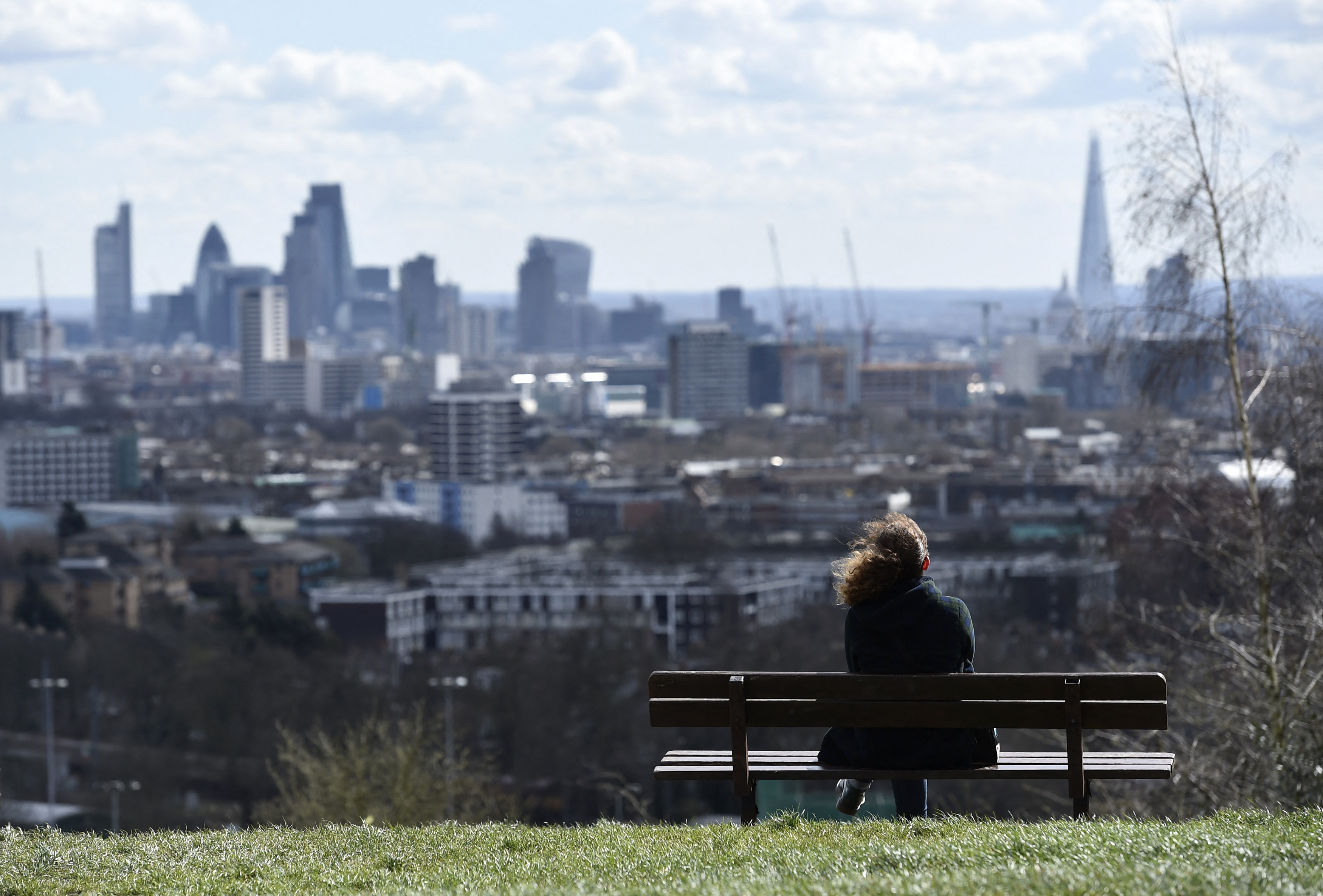 A woman looks towards the City of London financial district from Parliament Hill in north London
