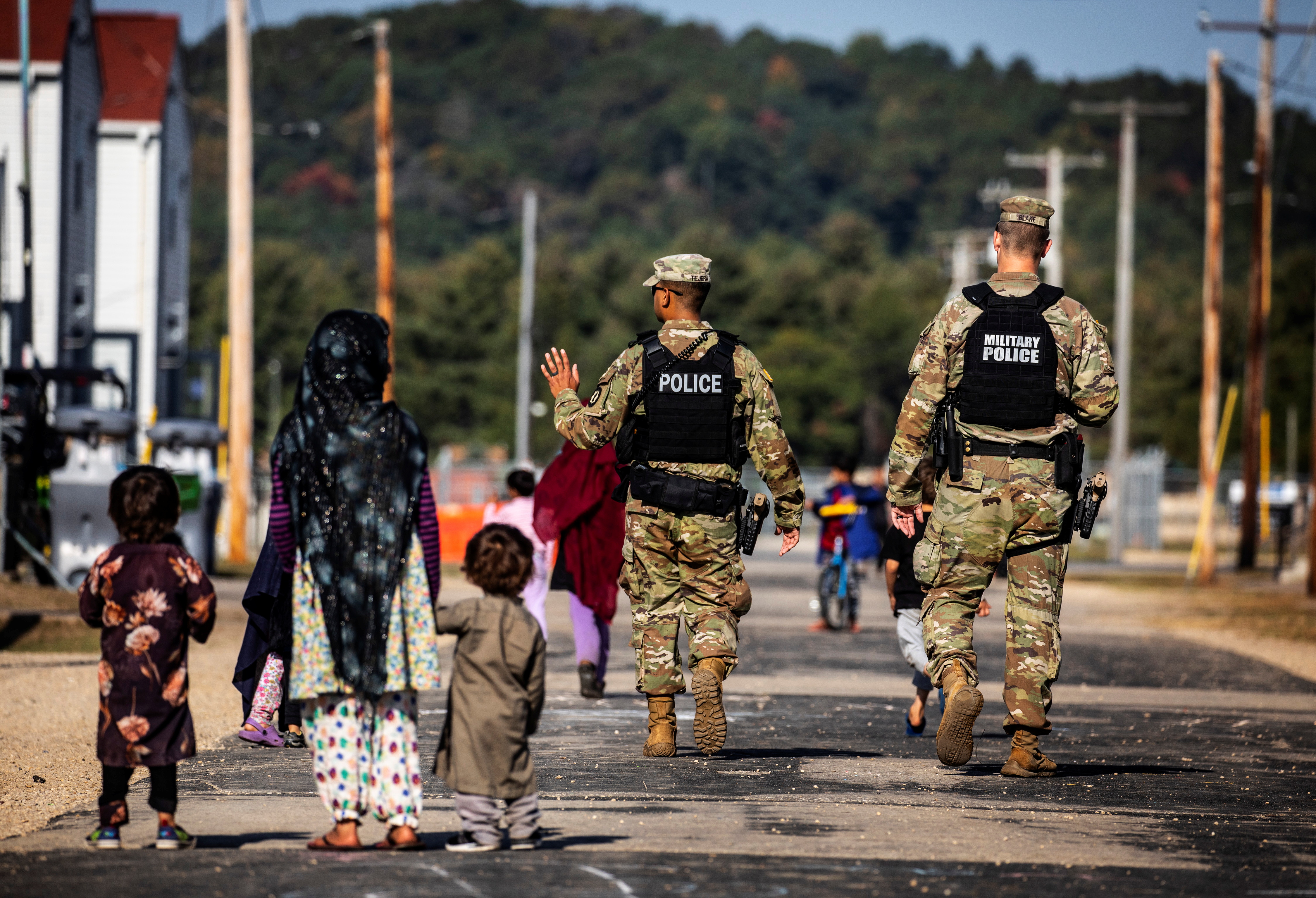 U.S. Military Police walk past Afghan refugees at the Village at Fort McCoy U.S. Army base, in Wisconsin, U.S., September 30, 2021. Barbara Davidson/Pool via REUTERS