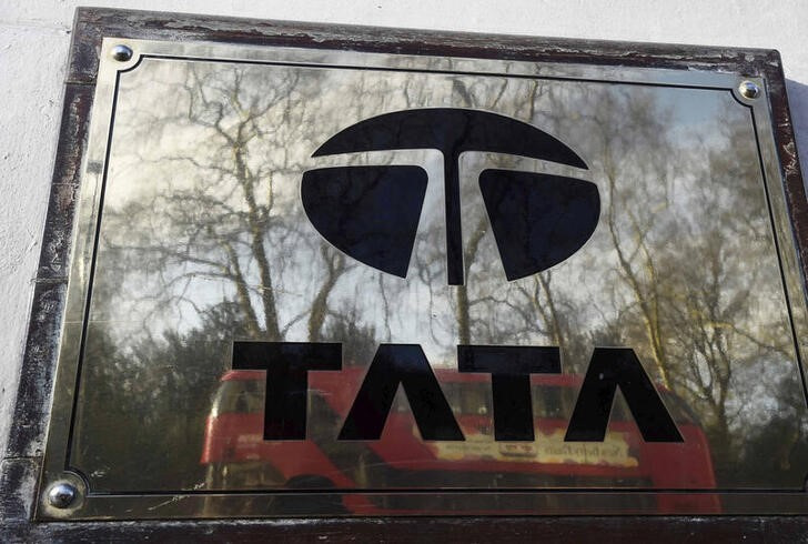 A bus is reflected in a Tata sign outside their offices in London