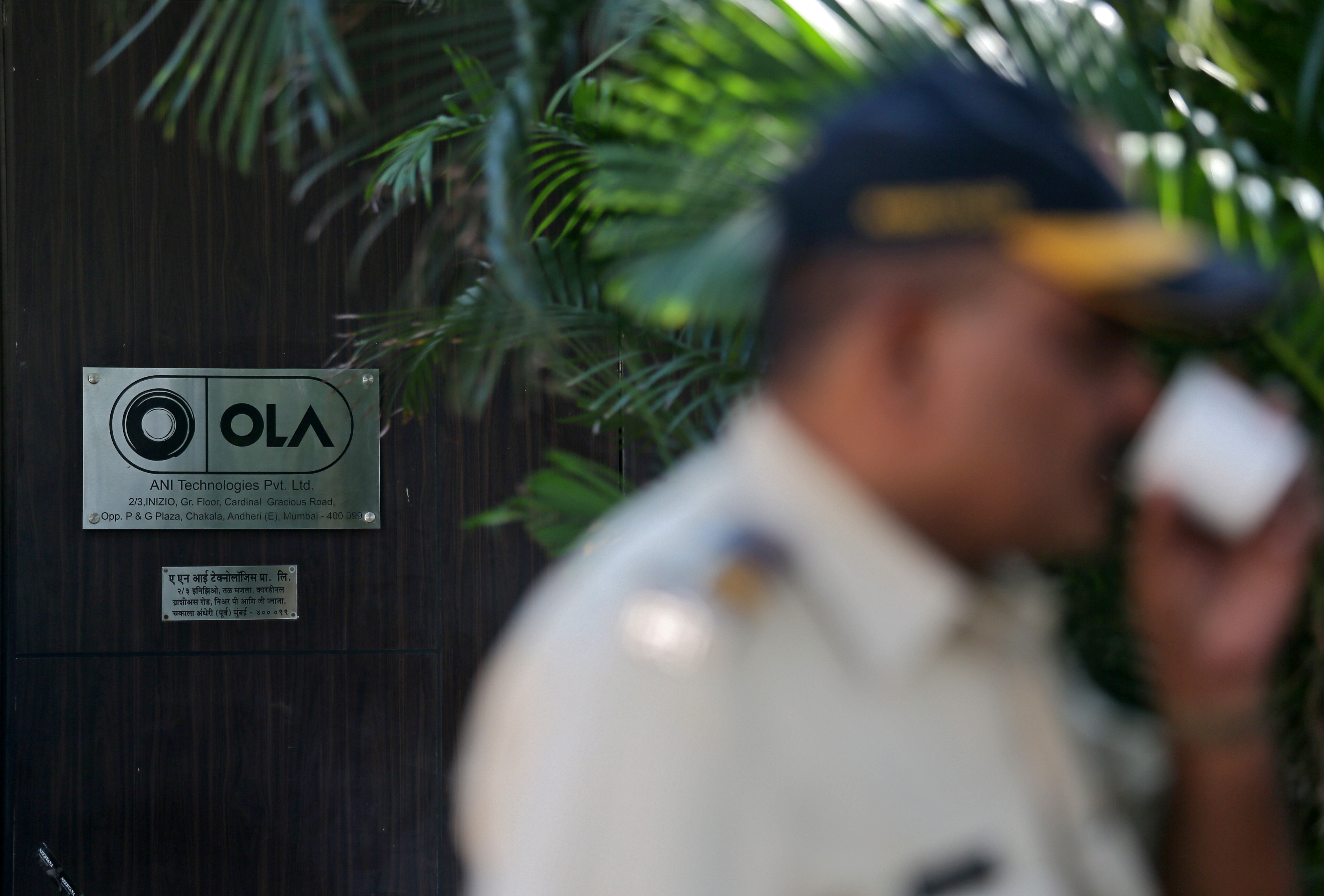 A policeman drinks tea in front of Ola's office in Mumbai