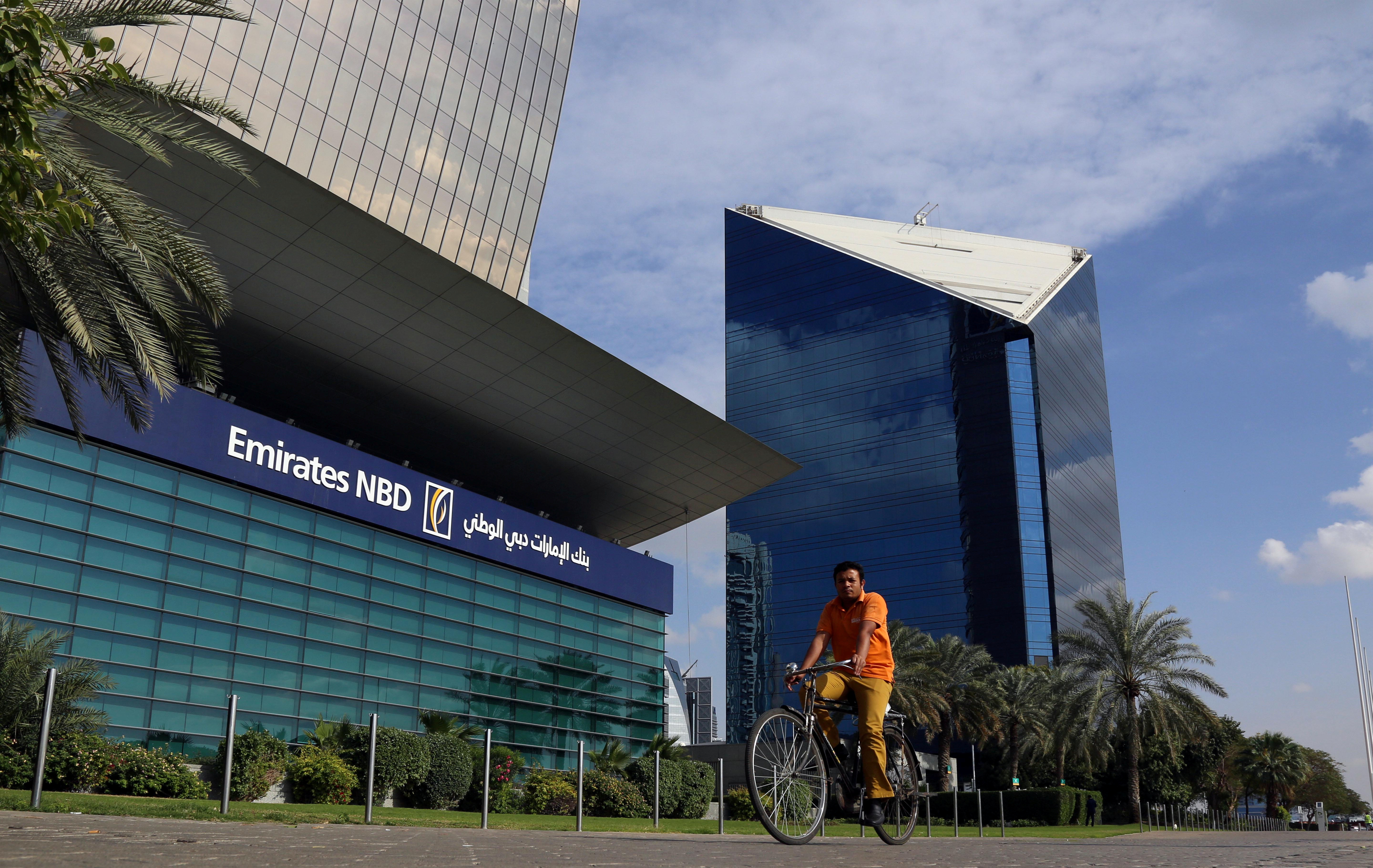 A man rides a bicycle past Emirates NBD head office in Dubai