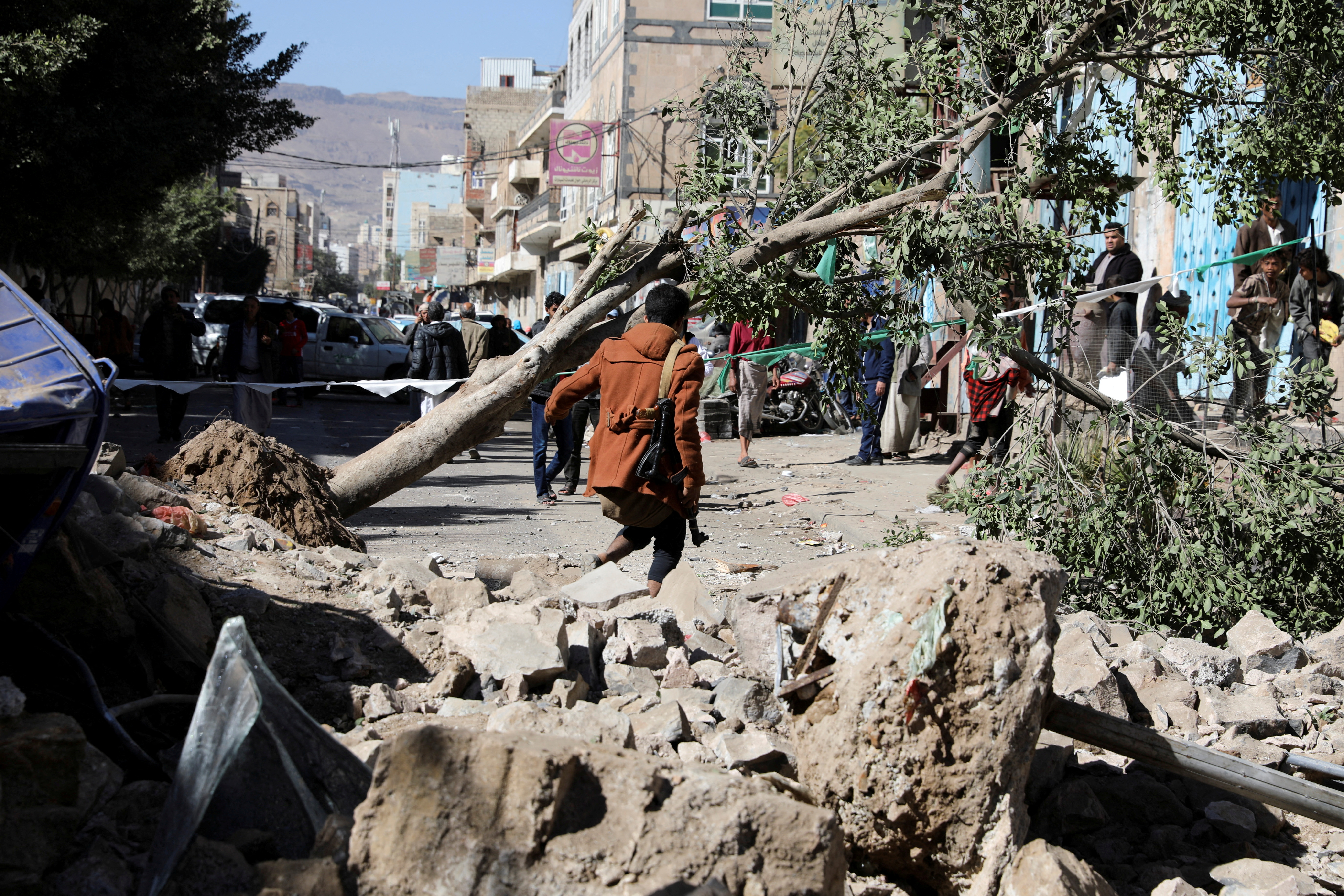 An armed man walks at the site of a Saudi-led air strike in Sanaa