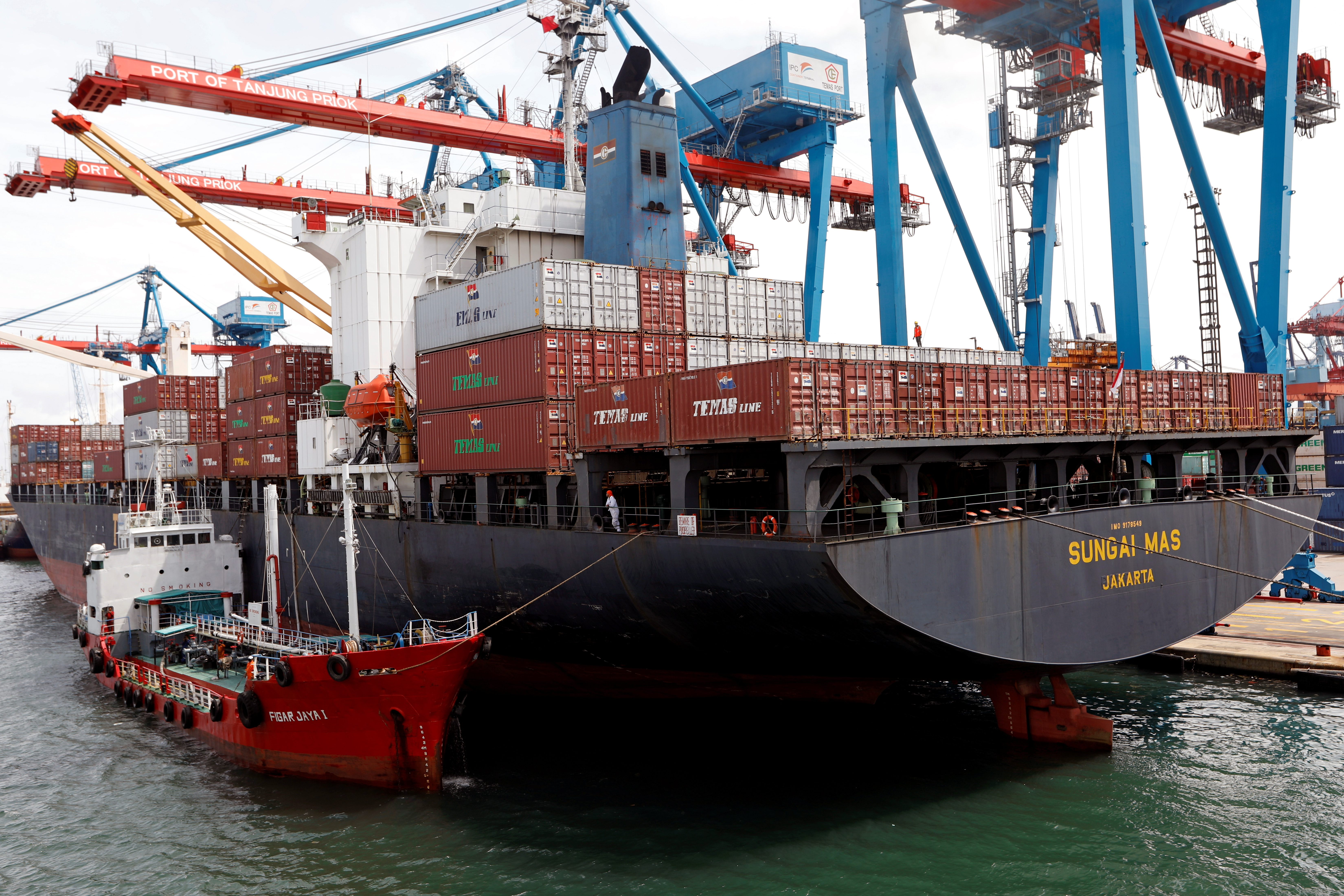 Pekerja terlihat di kapal memuat kontainer di Pelabuhan Tanjung Priok di Jakarta