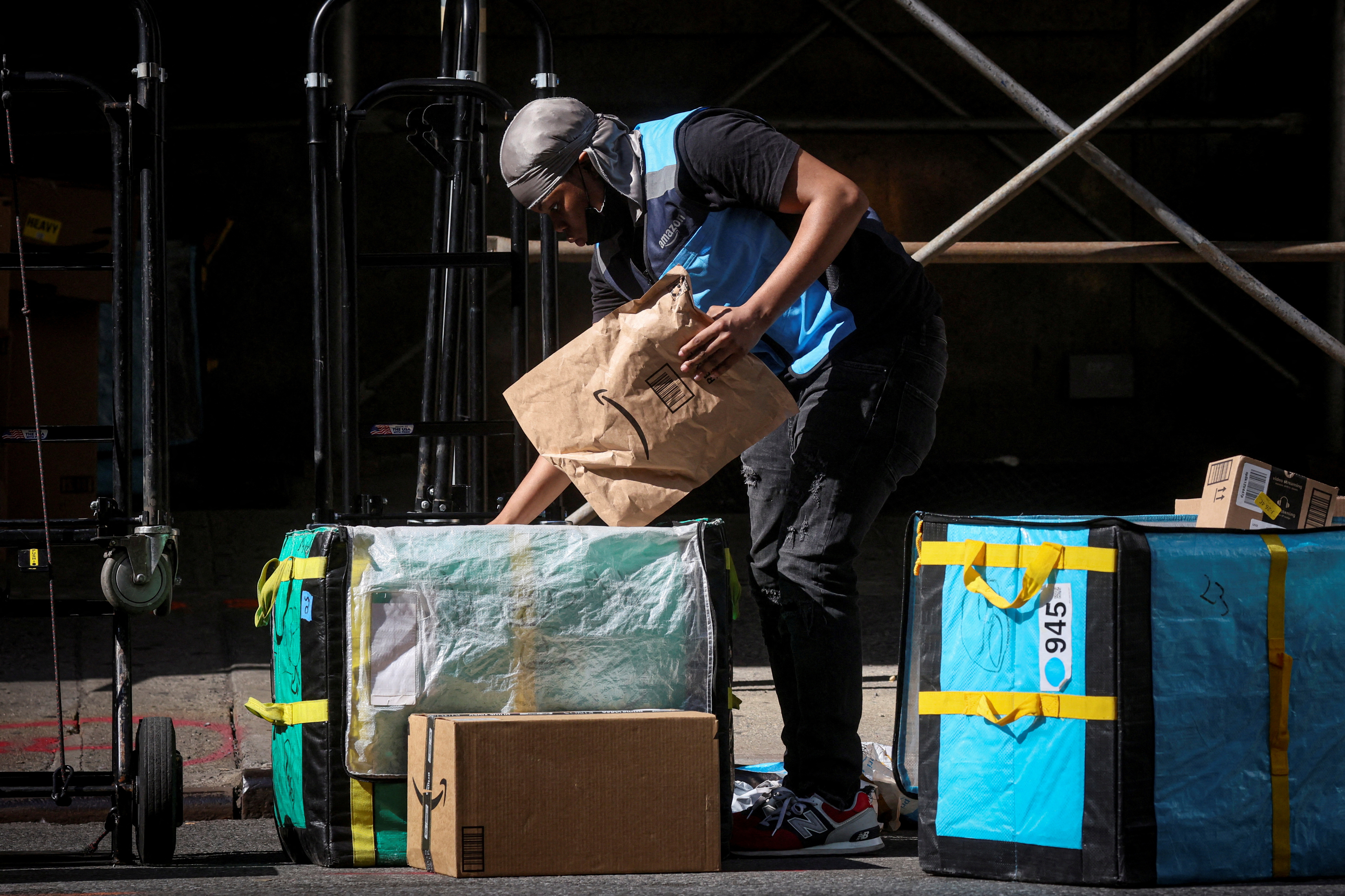 An Amazon delivery worker sorts packages out for delivery in the financial district of New York City