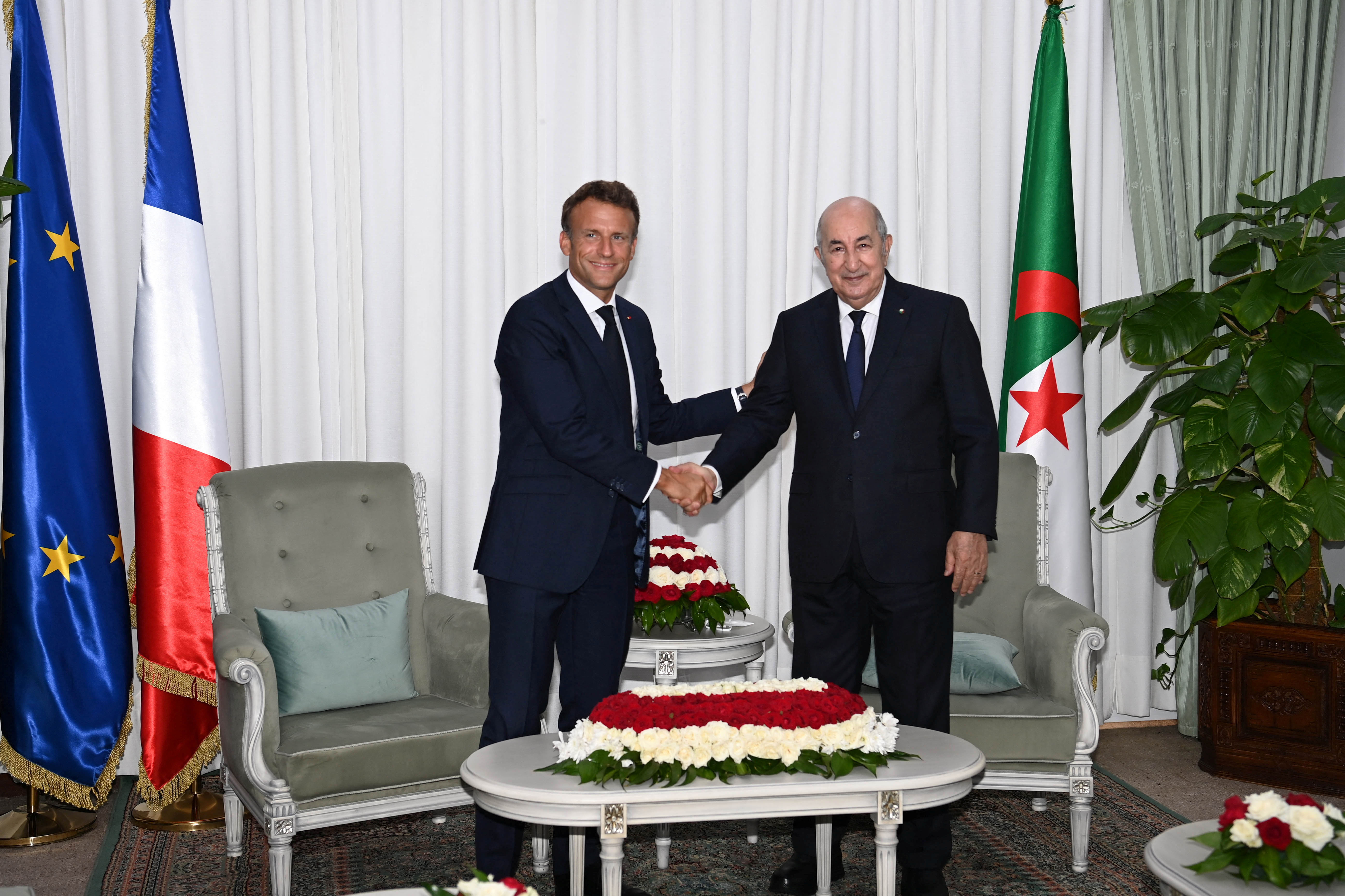 French President Emmanuel Macron shakes hand with Algerian President Abdelmadjid Tebboune, in Algiers