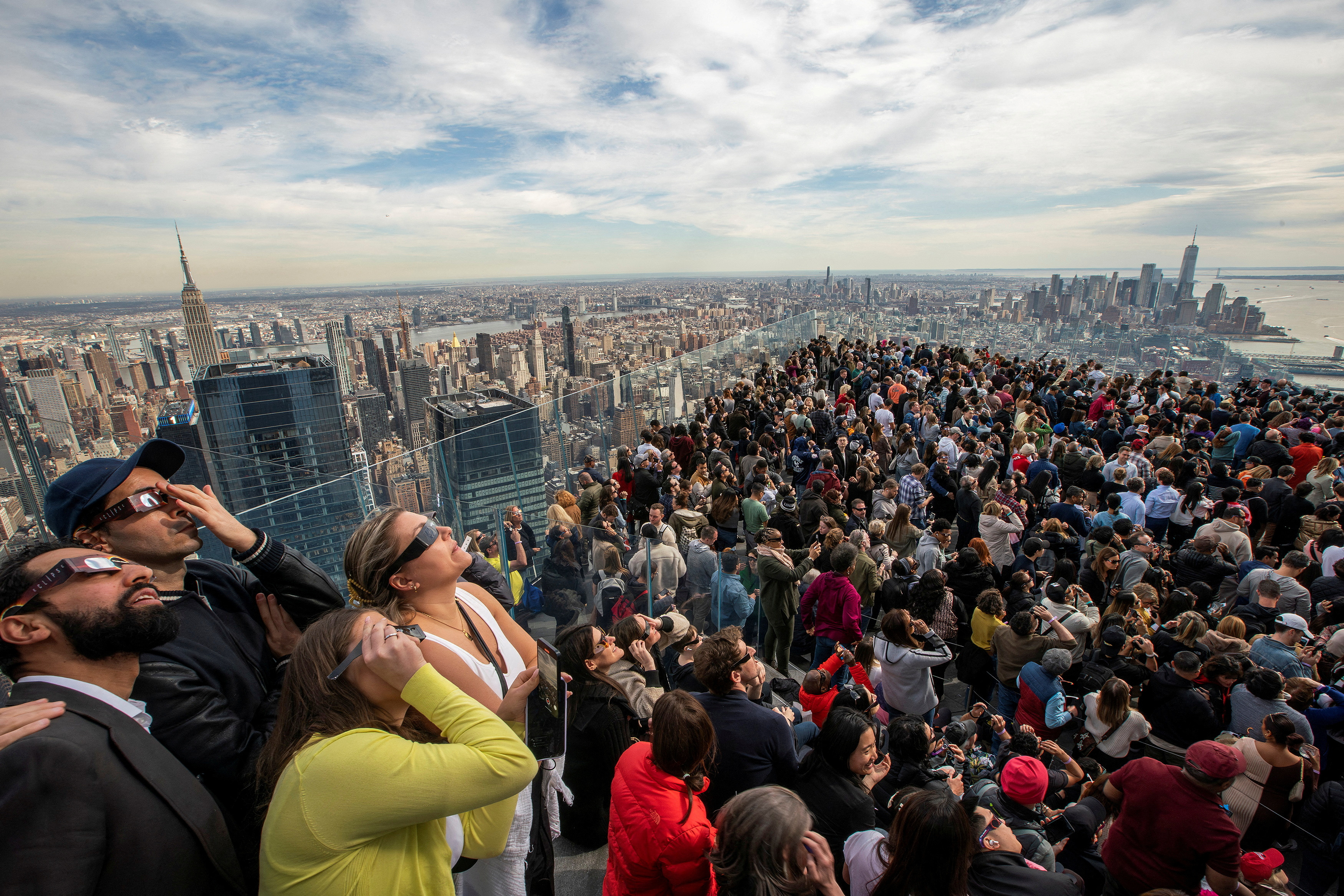 People watch the partial solar eclipse as they gather on the observation deck of Edge at Hudson Yards in New York City