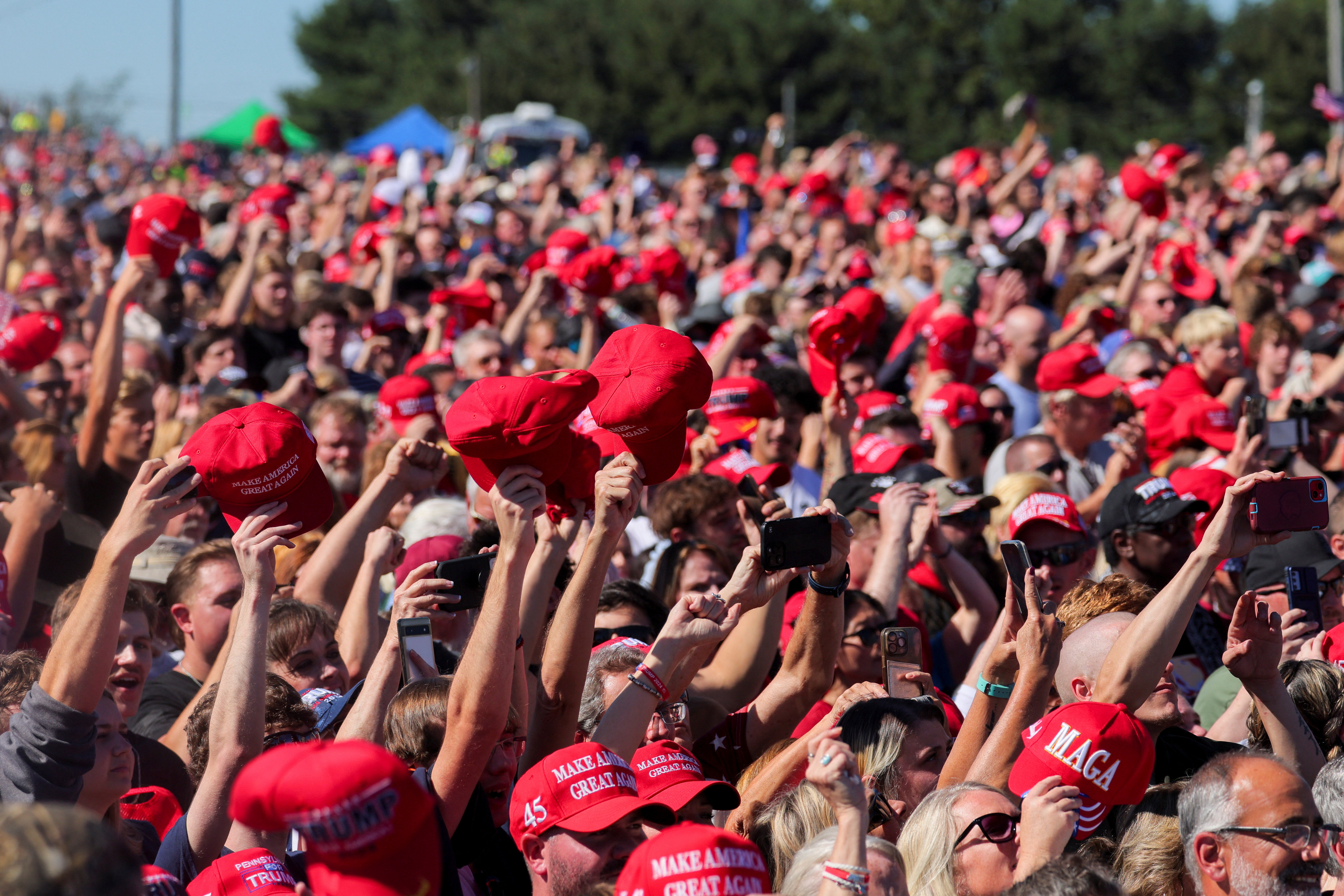 Supporters of Republican presidential nominee and former U.S. president Donald Trump raise MAGA hats, on the day Trump returns for a rally at the site of the July assassination attempt against him, in Butler, Pennsylvania, U.S., October 5, 2024. REUTERS/Brian Snyder 