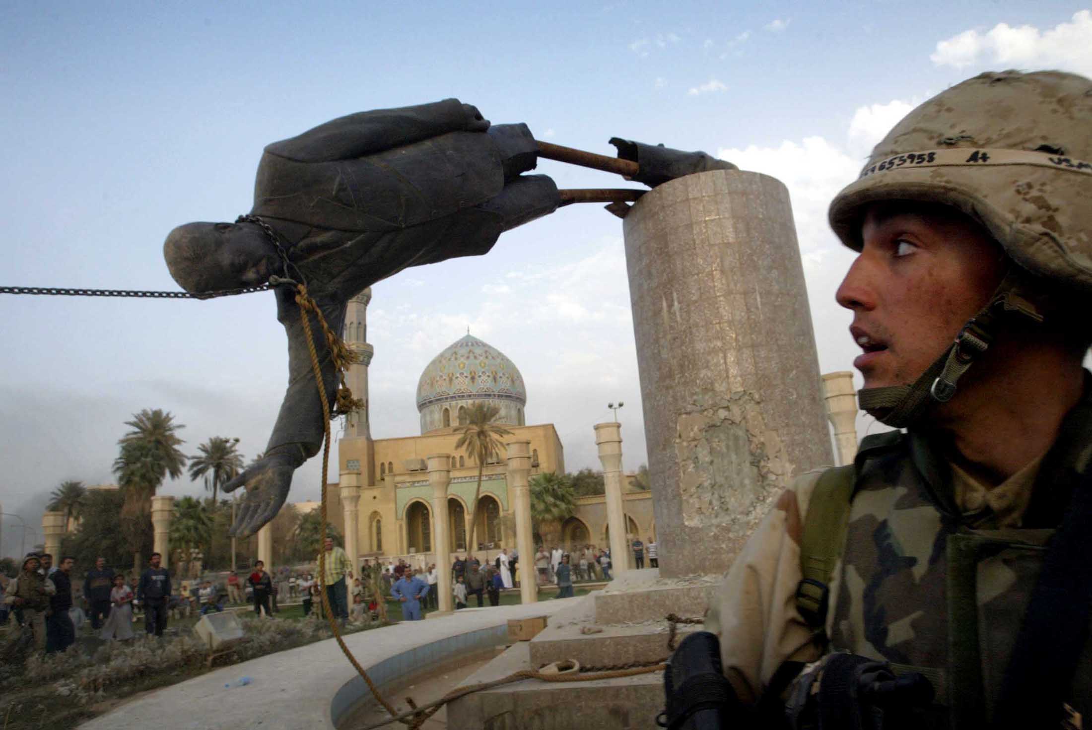 FILE PHOTO OF US MARINE WATCHES AS STATUE OF SADDAM HUSSEIN FALLS IN CENTRAL BAGHDAD.