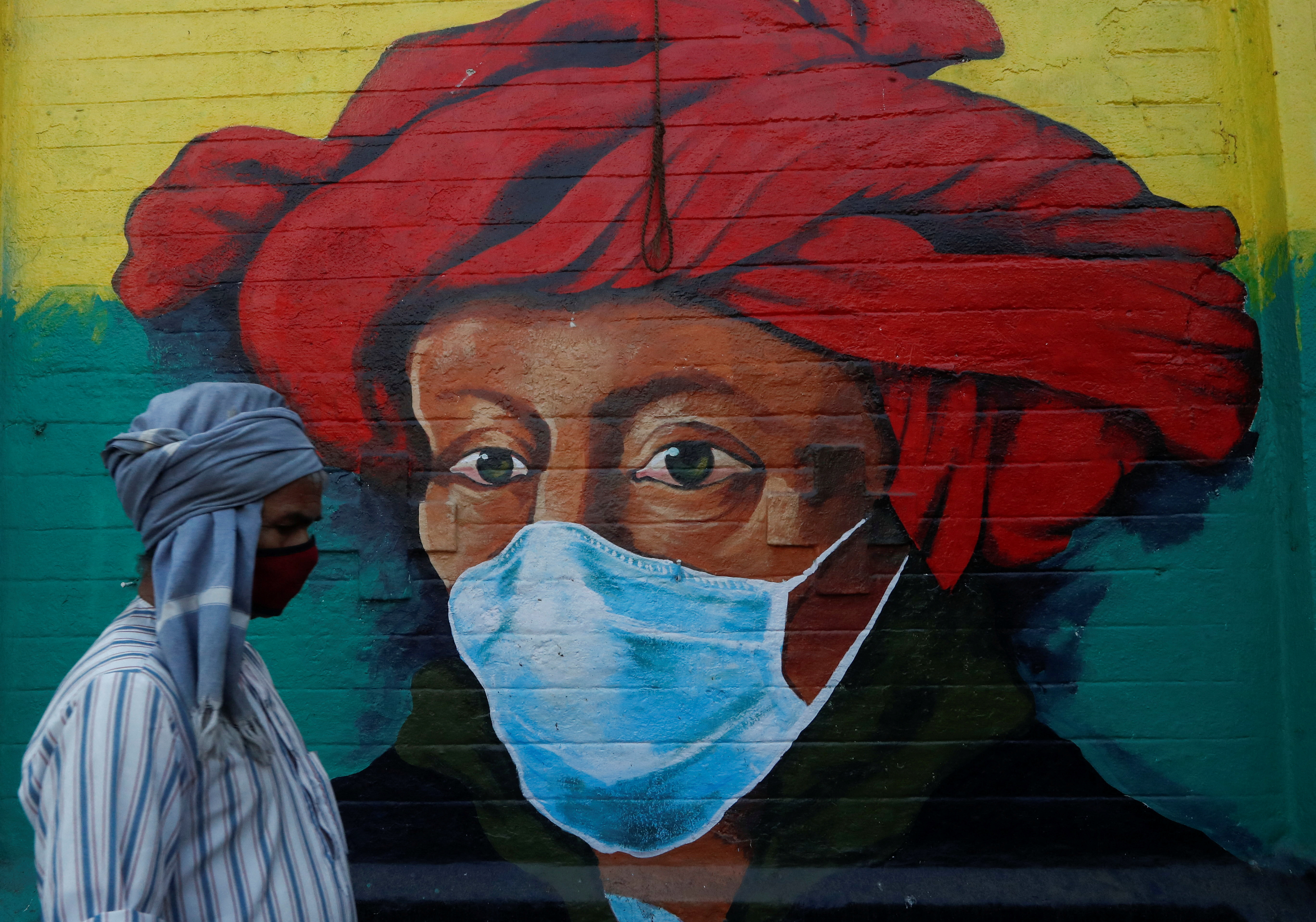 A man walks past a mural on a street, amidst the spread of the coronavirus disease (COVID-19), in Mumbai, India, January 10, 2022. REUTERS/Francis Mascarenhas