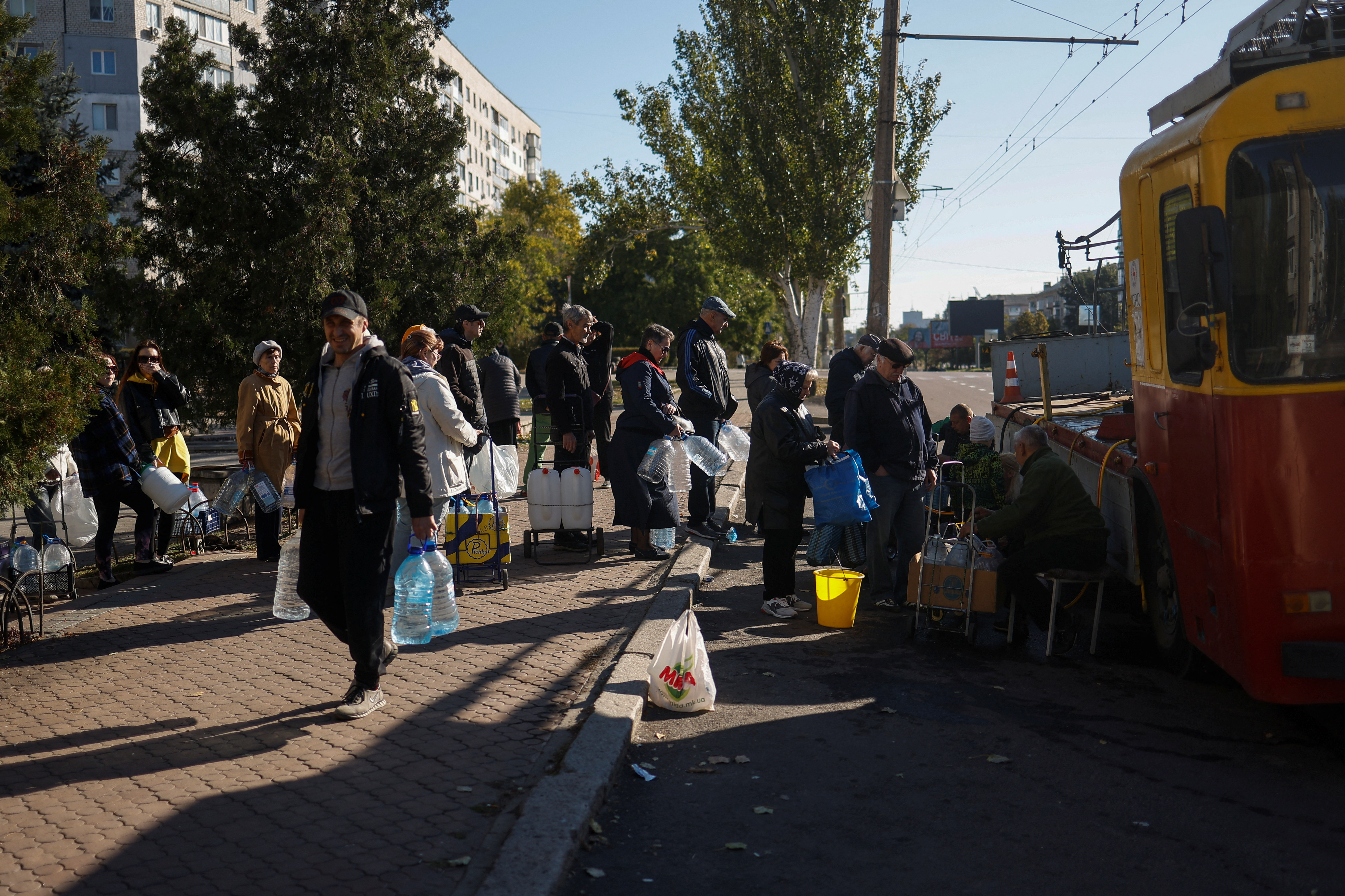 Local people stand in a queue to fill up bottles with fresh drinking water in Mykolaiv