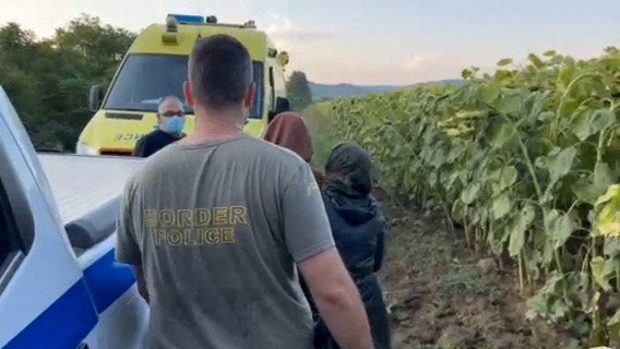 Migrants are escorted by a Greek border police officer, in the region of Evros