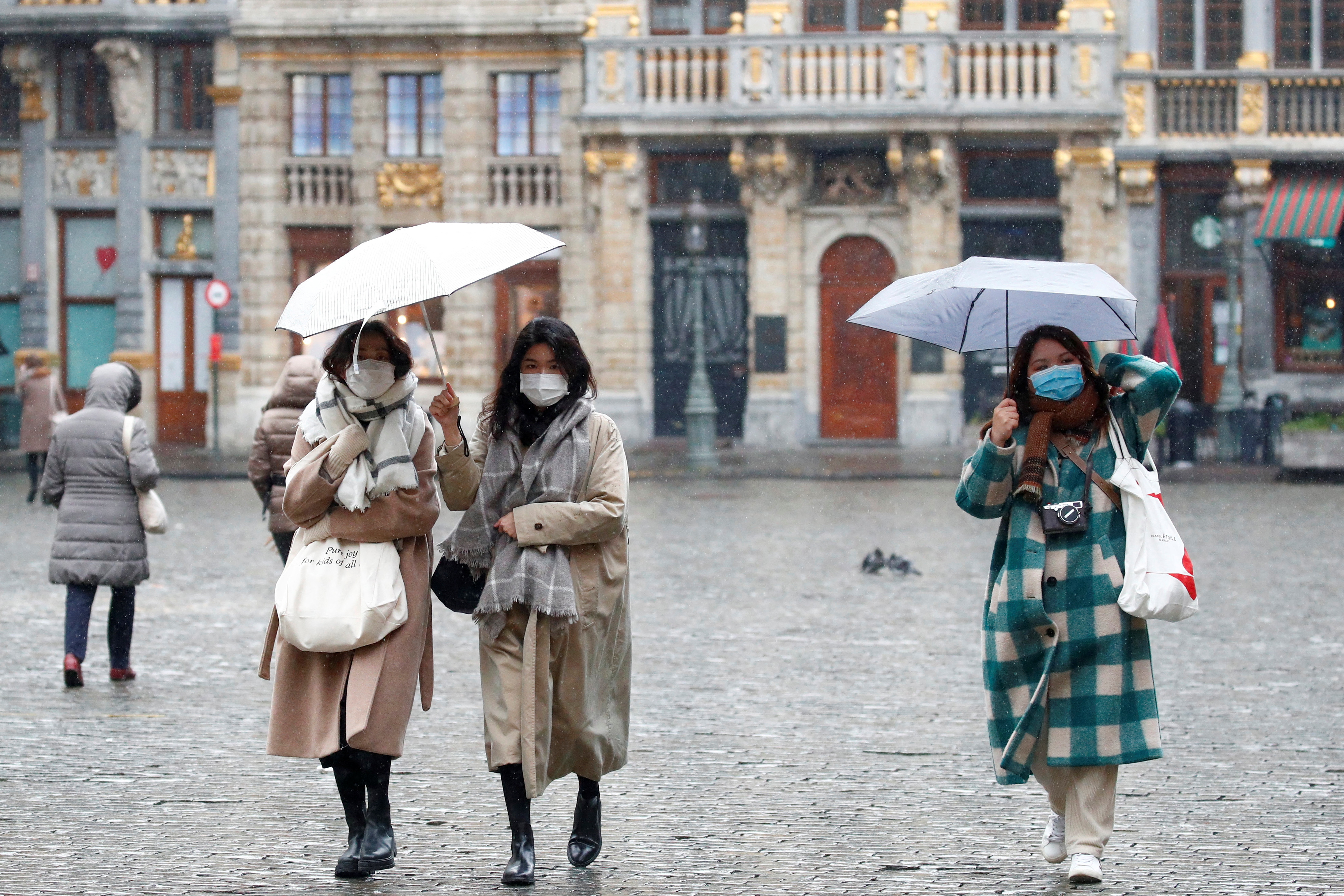 People wearing protective face masks walk on a street in Brussels