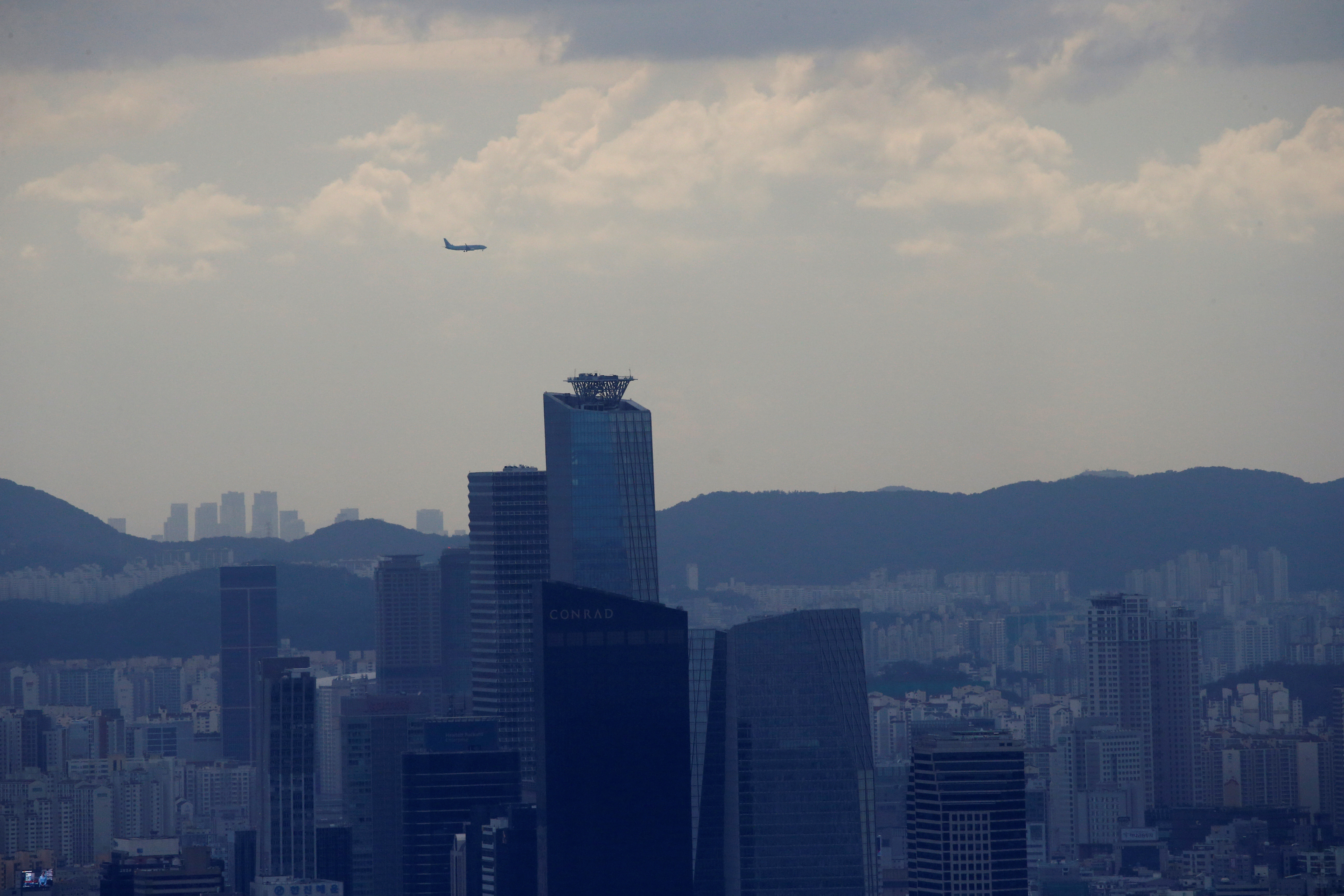 A plane flies over commercial buildings in Seoul