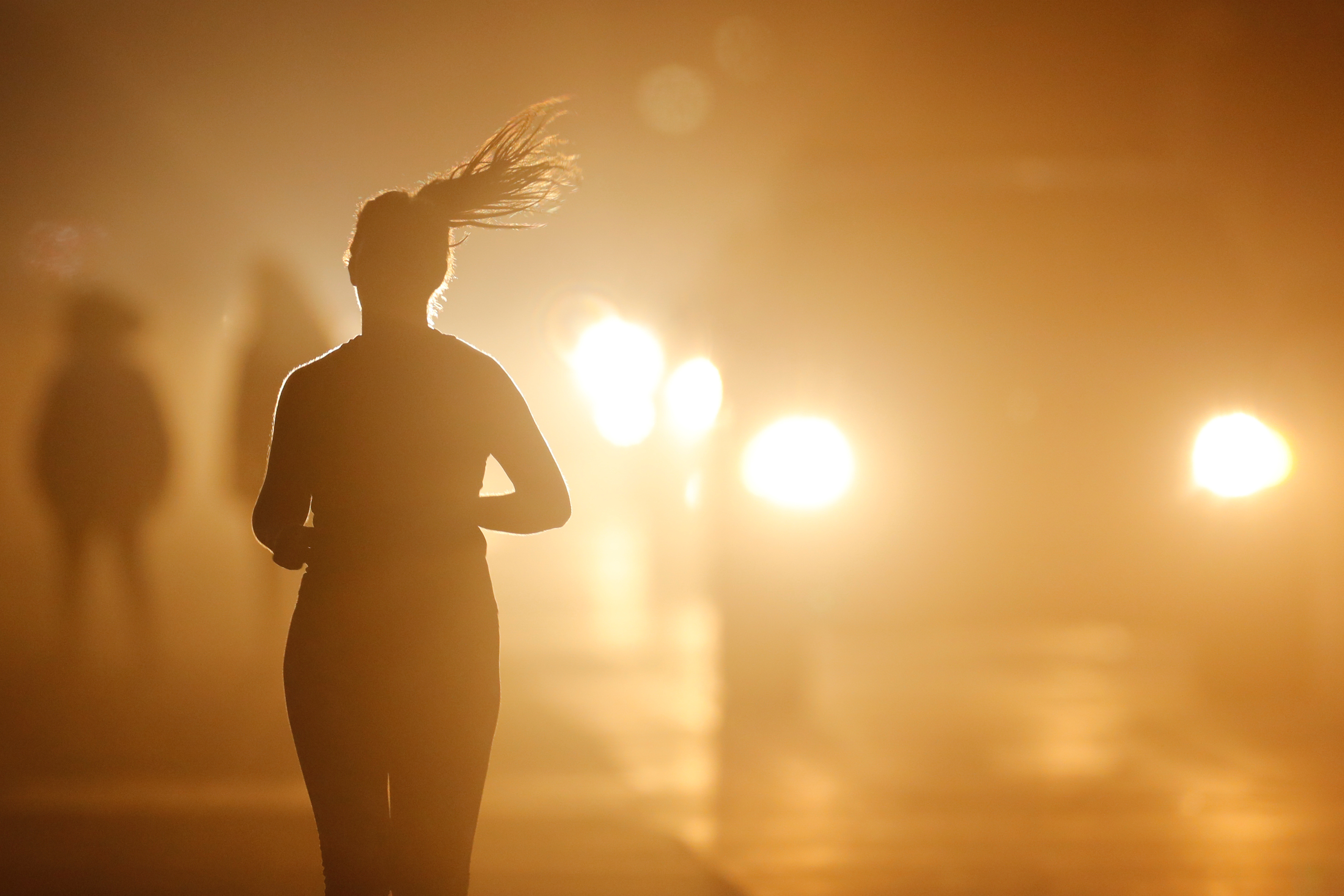 A women jogs along a roadside as temperatures cool off after sunset in Oceanside, California