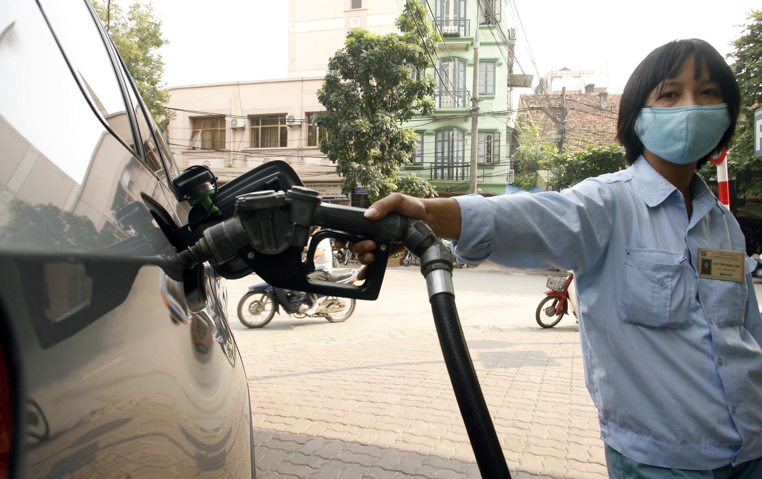 Woman pumps petrol into car at petrol station in Hanoi