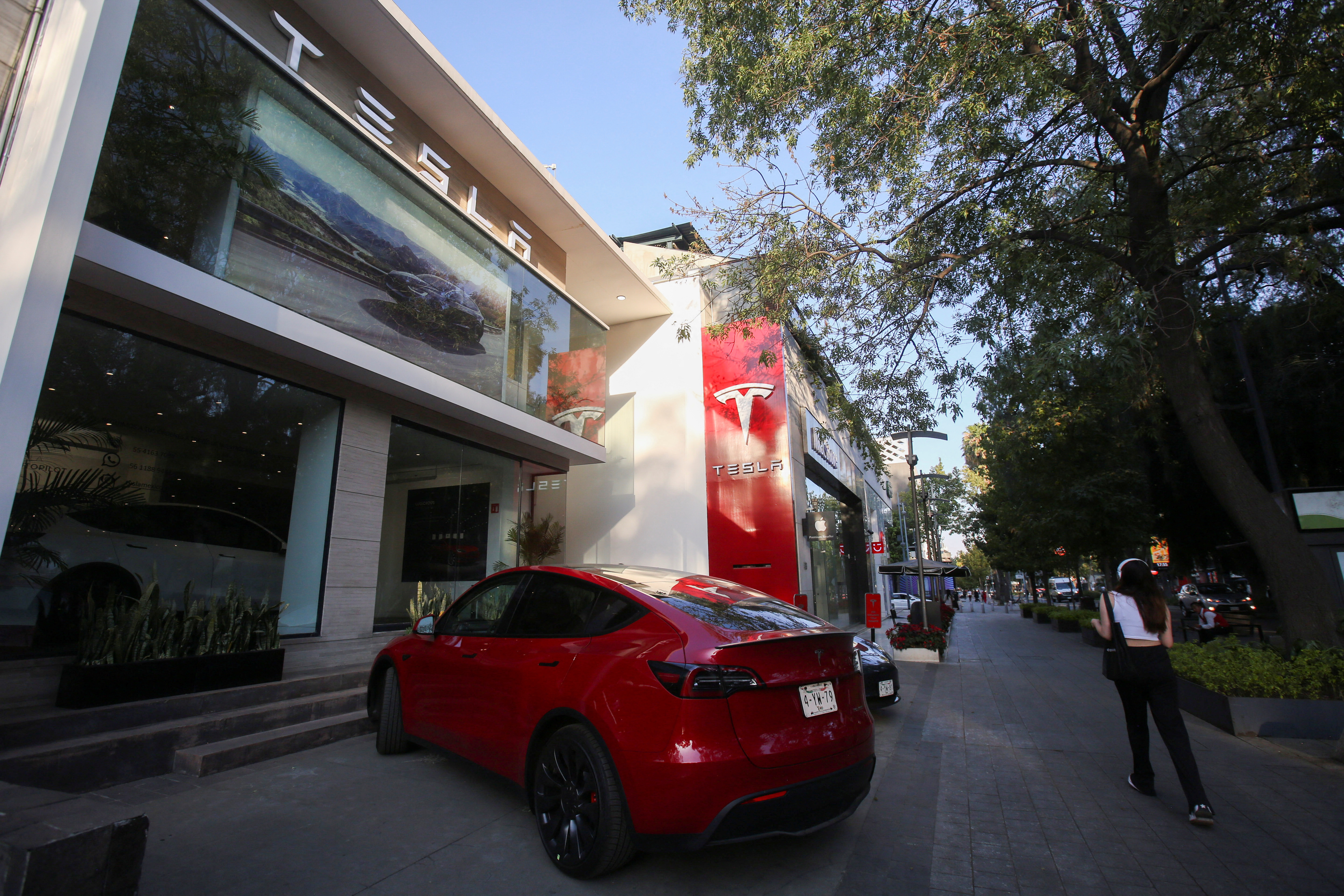 A woman walks by a Tesla dealership in Mexico City