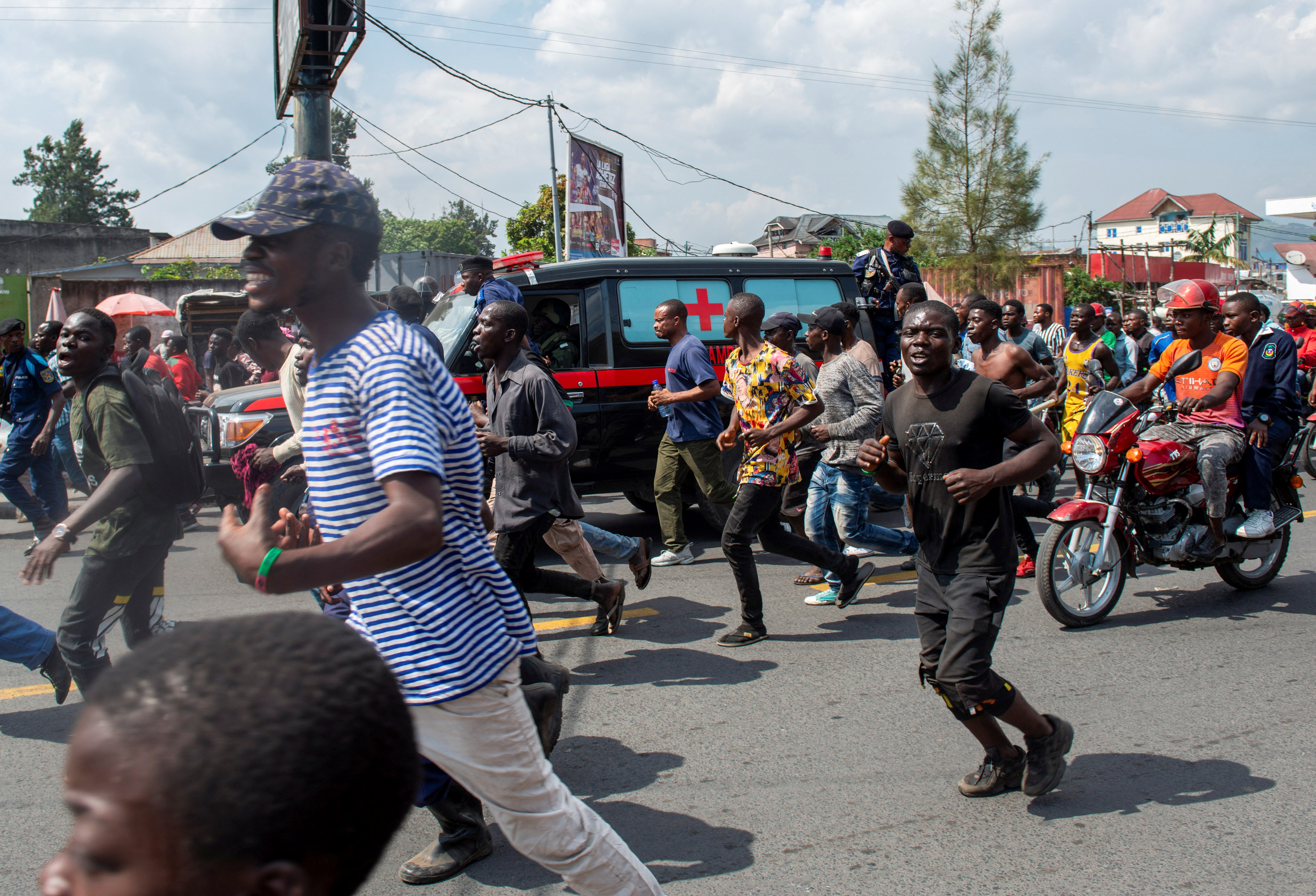 Civilians cheer as they escort a military ambulance carrying the body of a Congolese soldier shot dead in Rwanda