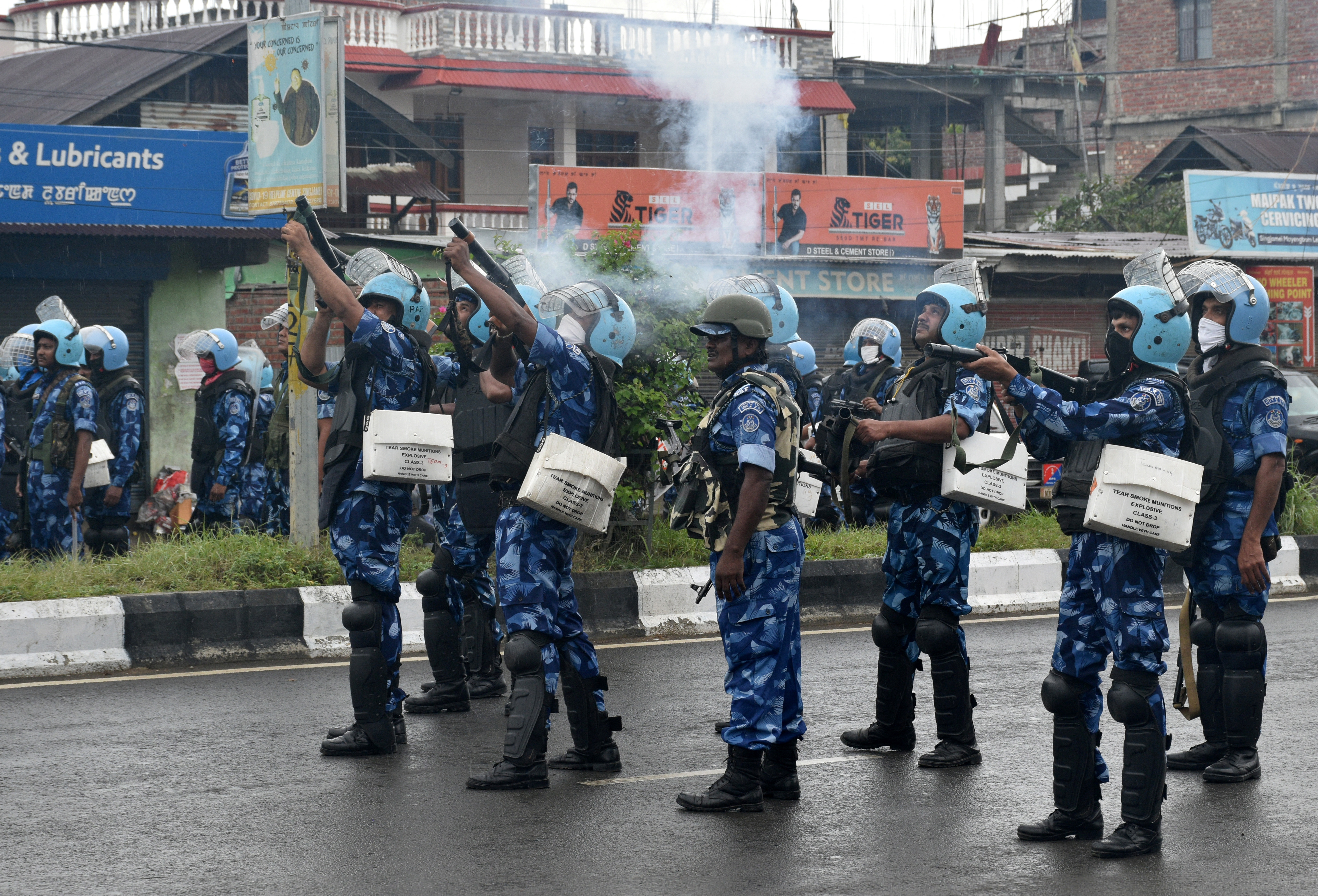 Riot police officers fire tear smoke shells to disperse demonstrators, in Imphal