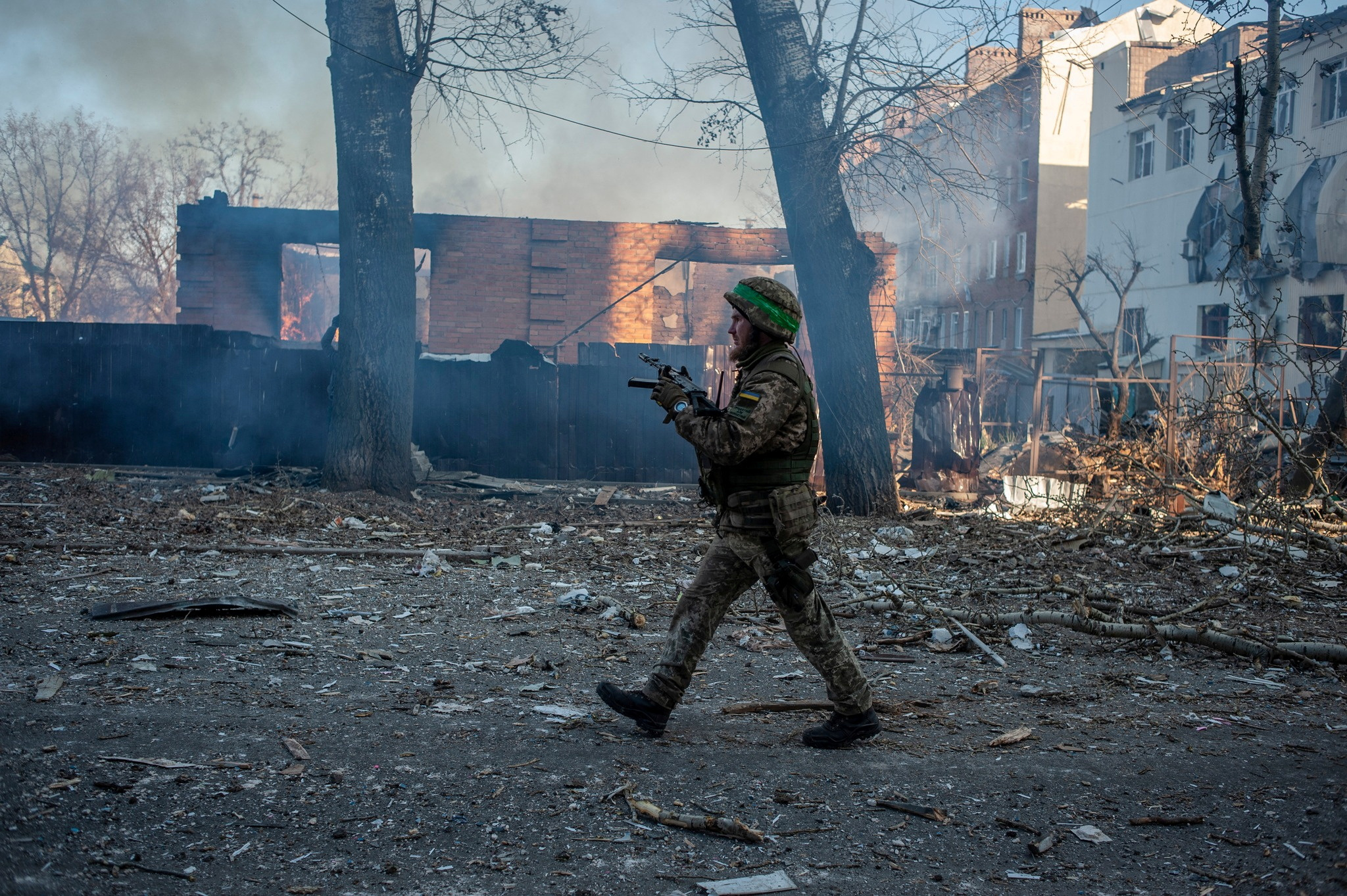 Ukrainian service member walks next to a burning building in the frontline town of Bakhmut