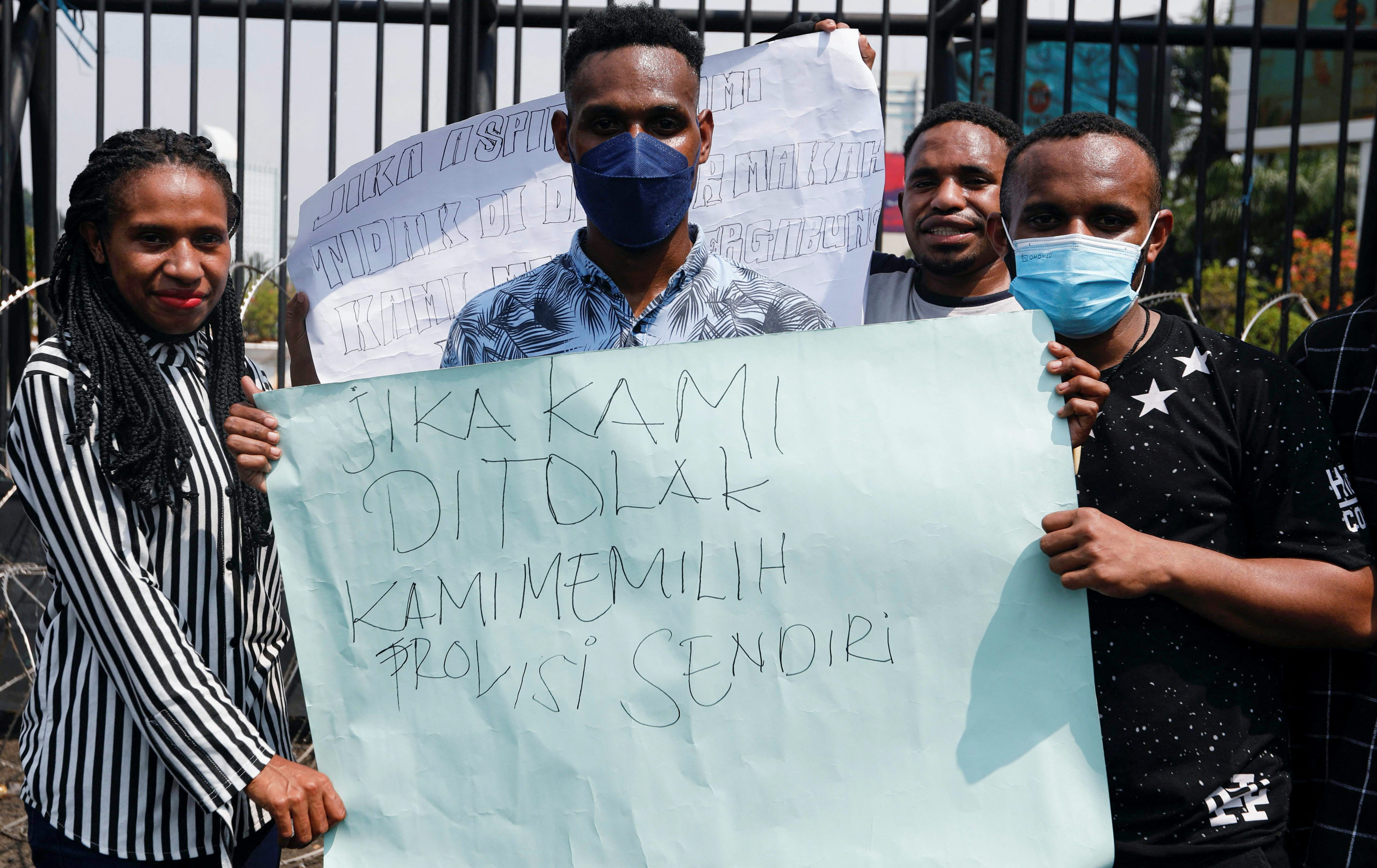Demonstrators hold a sign as they protest outside the Indonesian Parliament following a bill passed by legislators to create three new provinces in its underdeveloped region of Papua, in Jakarta