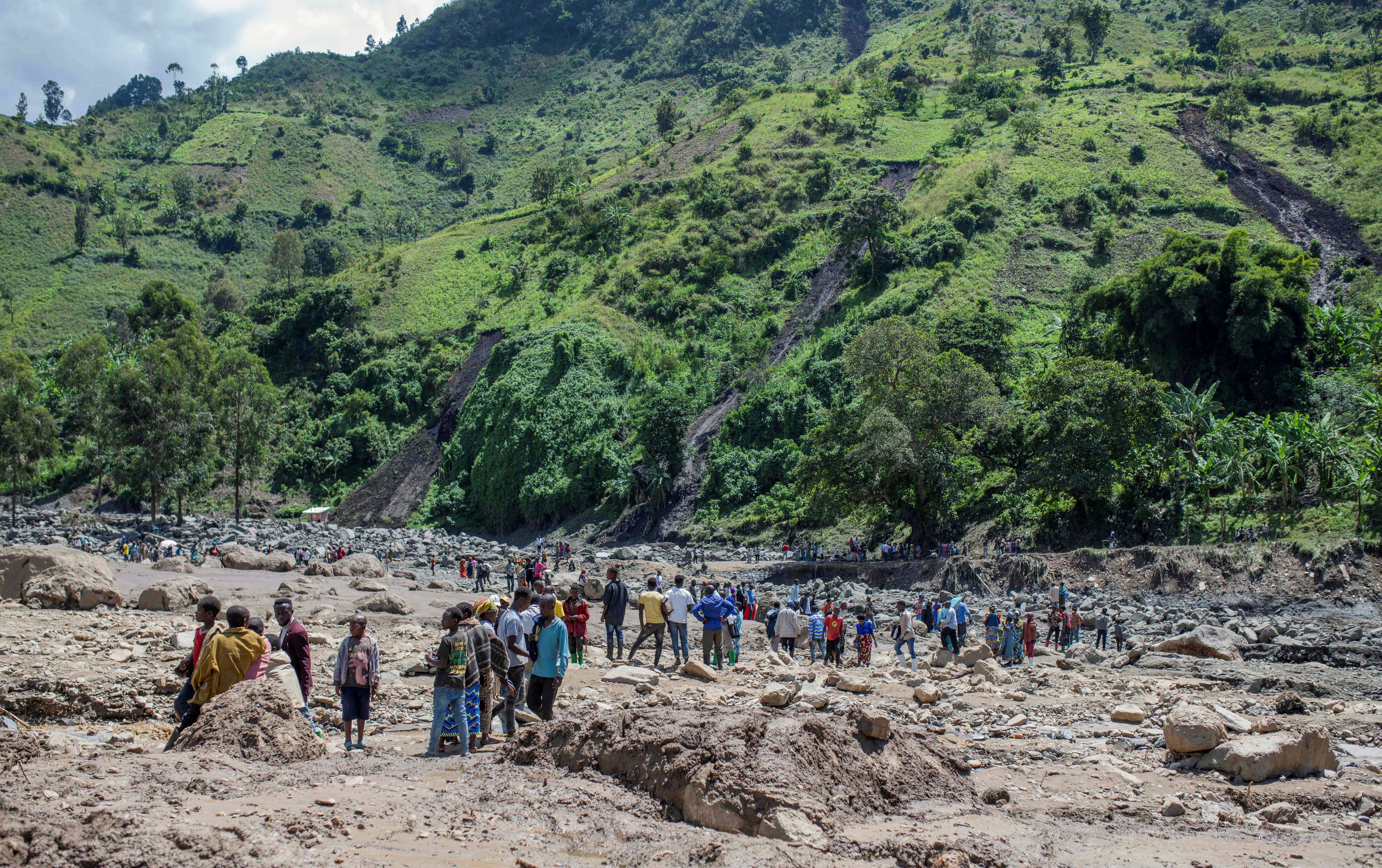 Congolese civilians gather after the death of their family members following rains that destroyed buildings and forced aid workers to gather mud-clad corpses into piles in the village of Nyamukubi