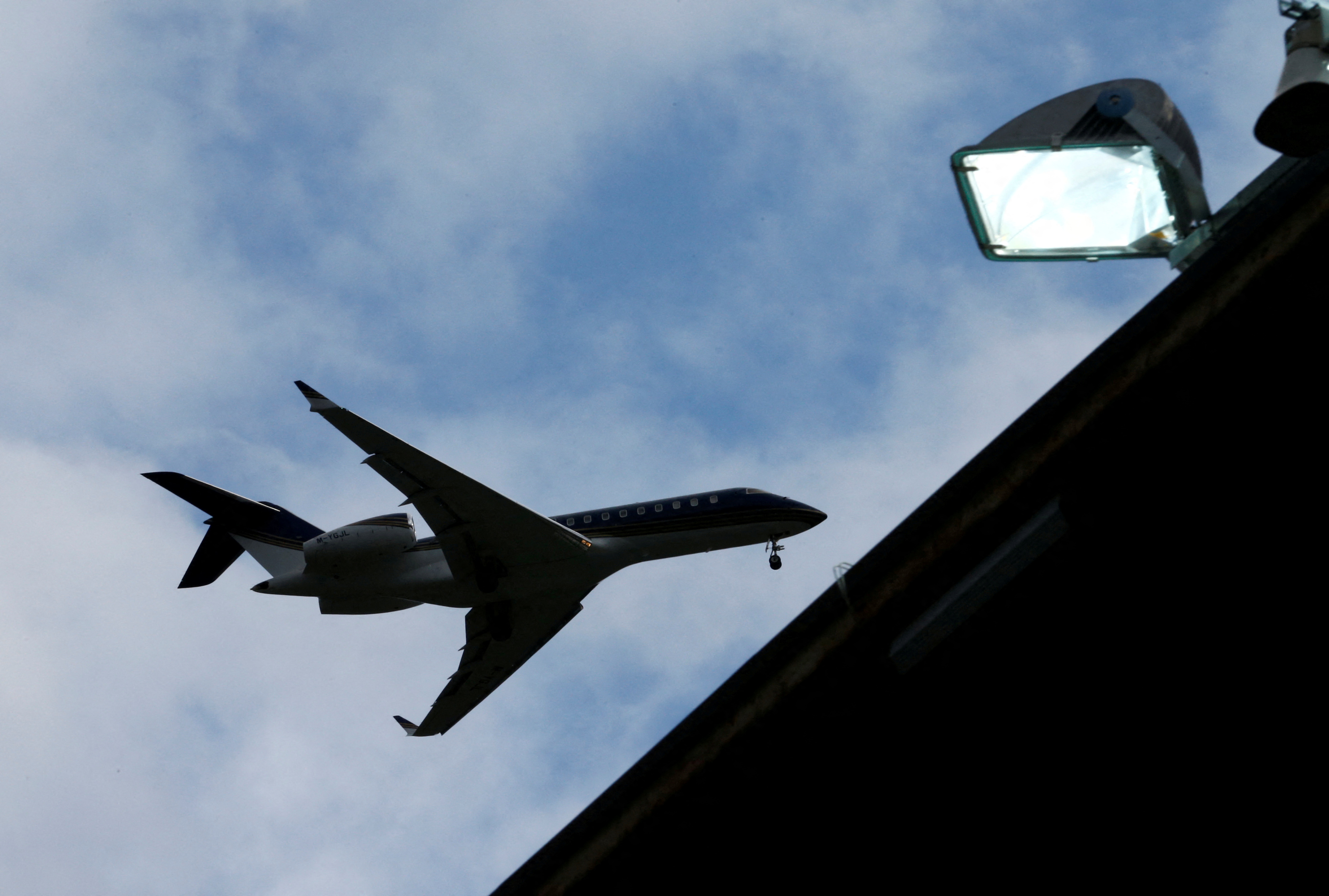 A Bombardier BD-700 aircraft is pictured above football stadium lights at Sion Airport