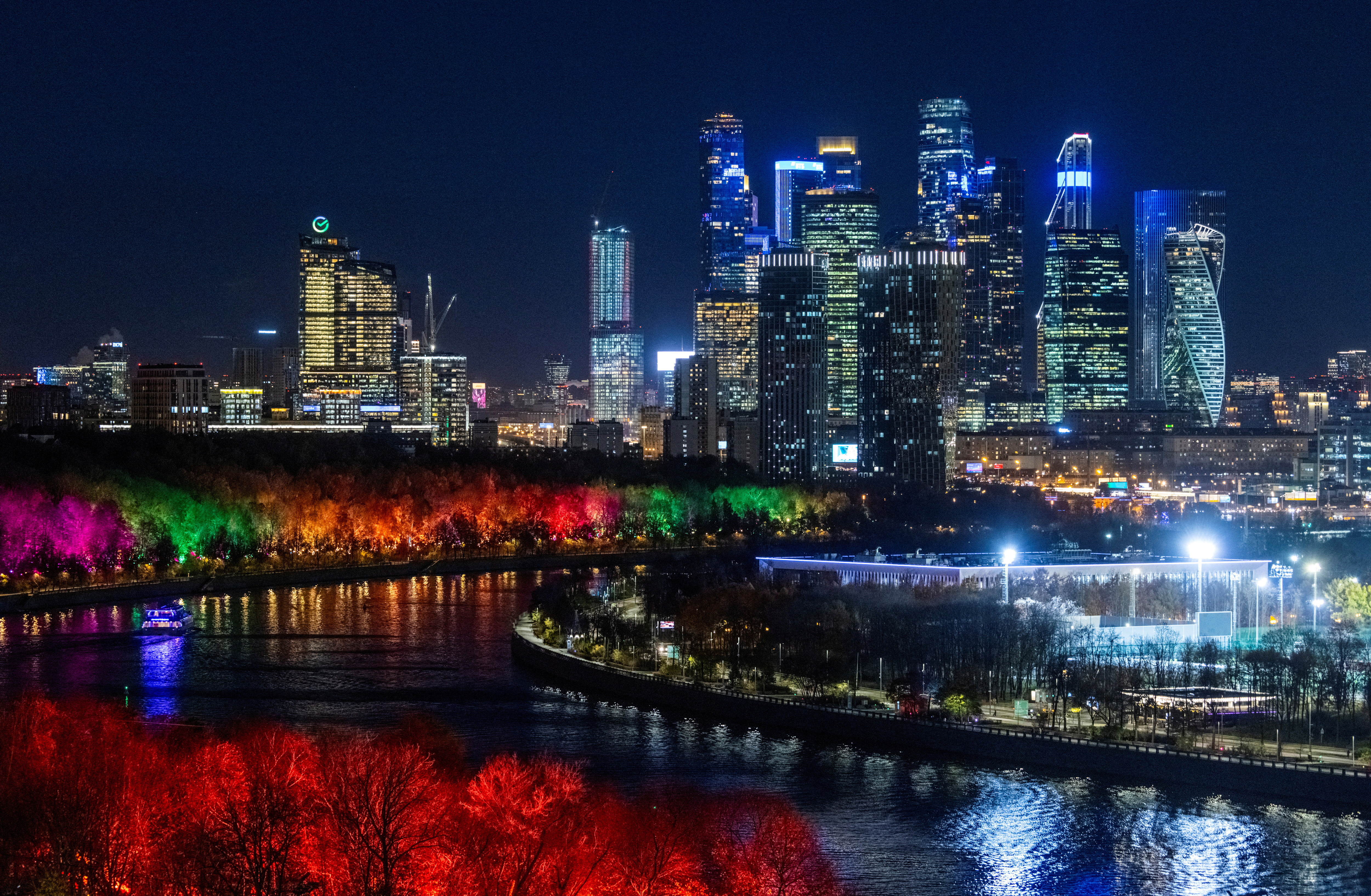 A view of Moscow City International Business District and Moskva river with its embankment illuminated with colorful lights in Moscow