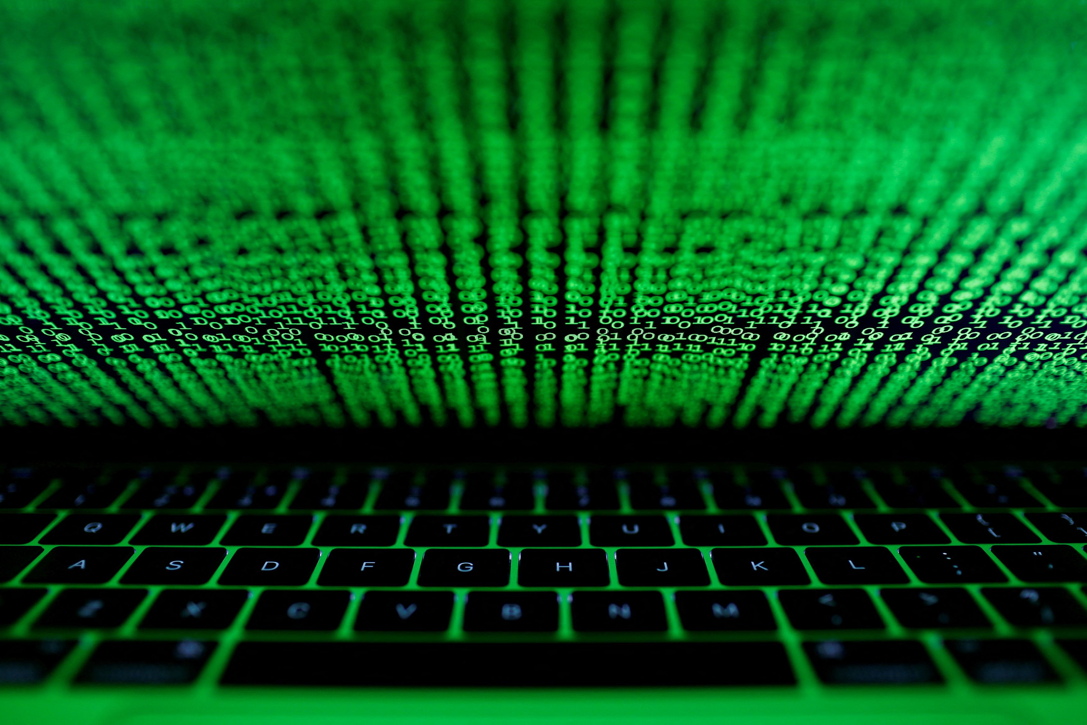 A computer keyboard lit by a displayed cyber code is seen in this illustration picture