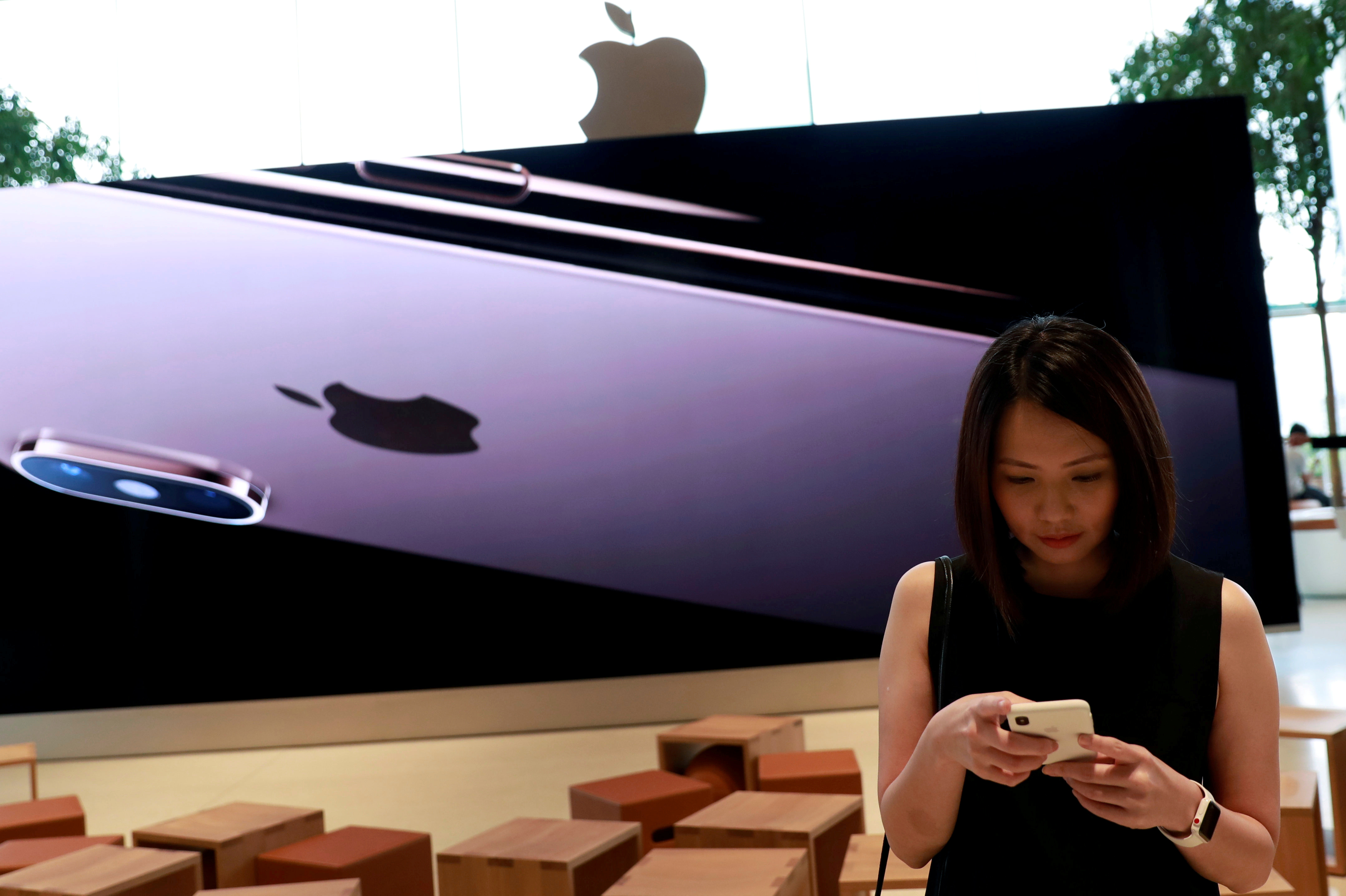 Woman checks her phone at a flagship Apple store at Iconsiam shopping mall in Bangkok