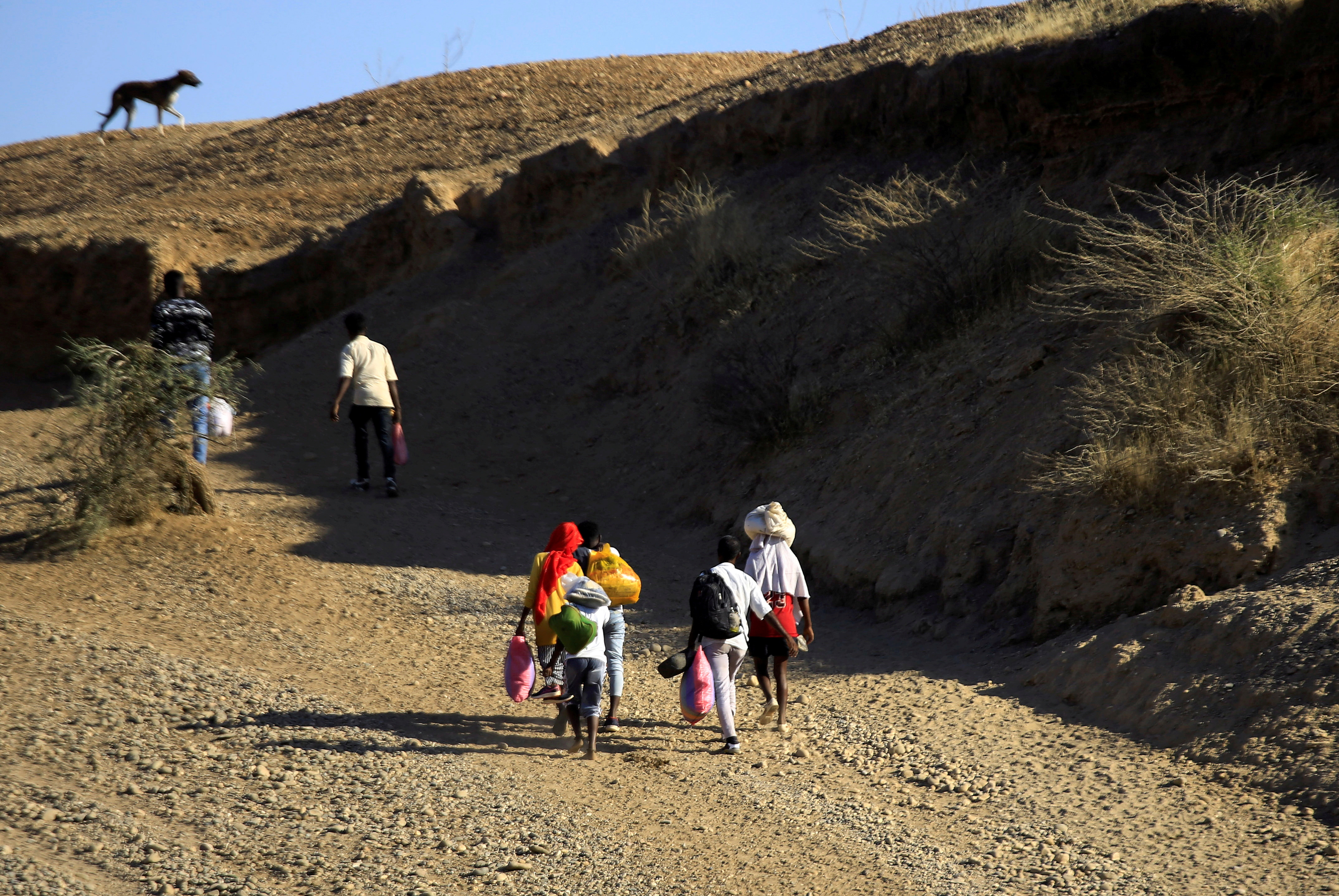 Ethiopians, who fled the ongoing fighting in Tigray region, carry their belongings after crossing the Setit River on the Sudan-Ethiopia border, in the eastern Kassala state, Sudan December 16, 2020. REUTERS/Mohamed Nureldin Abdallah/File Photo