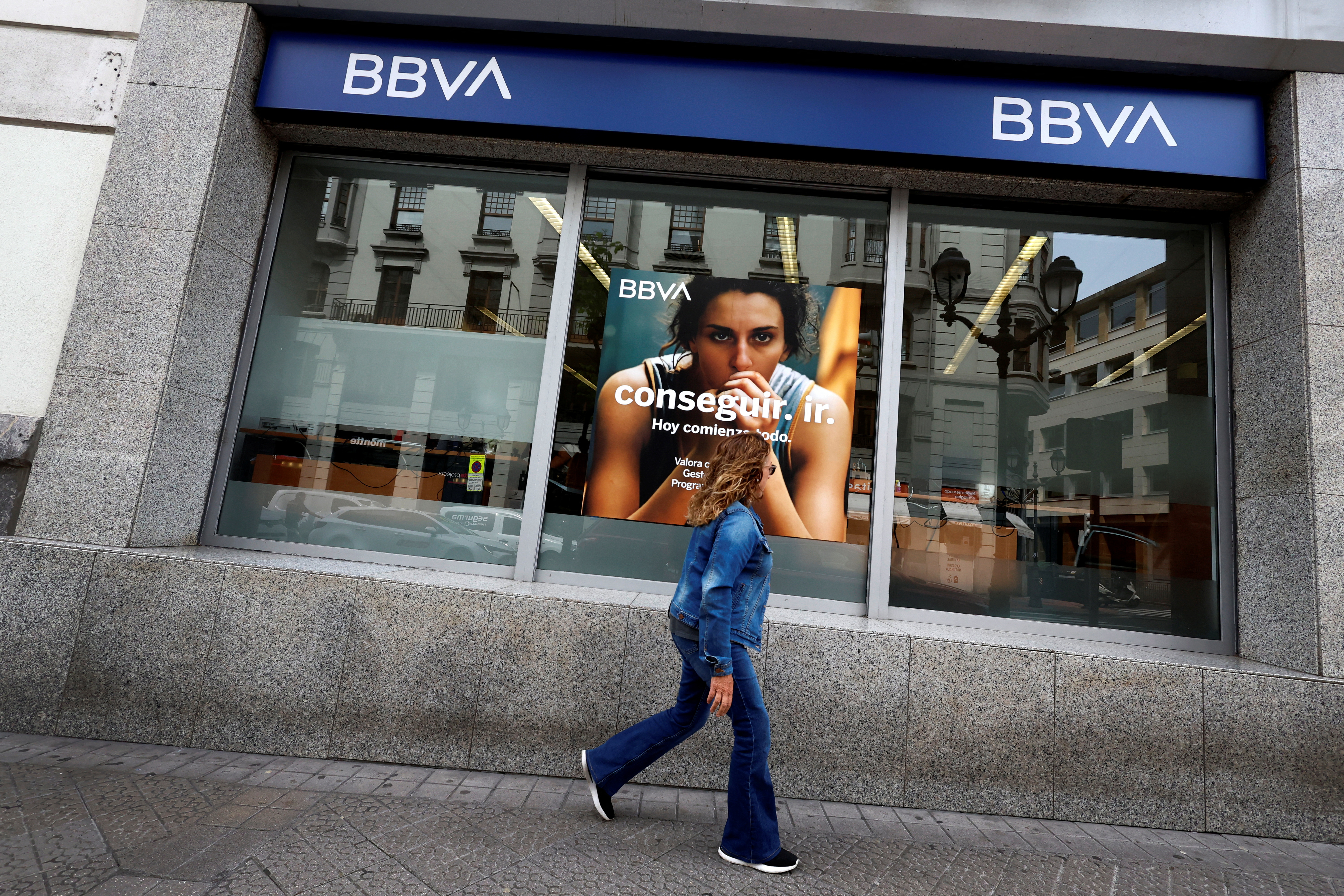 A woman walks past a branch of Spain's BBVA bank in Bilbao