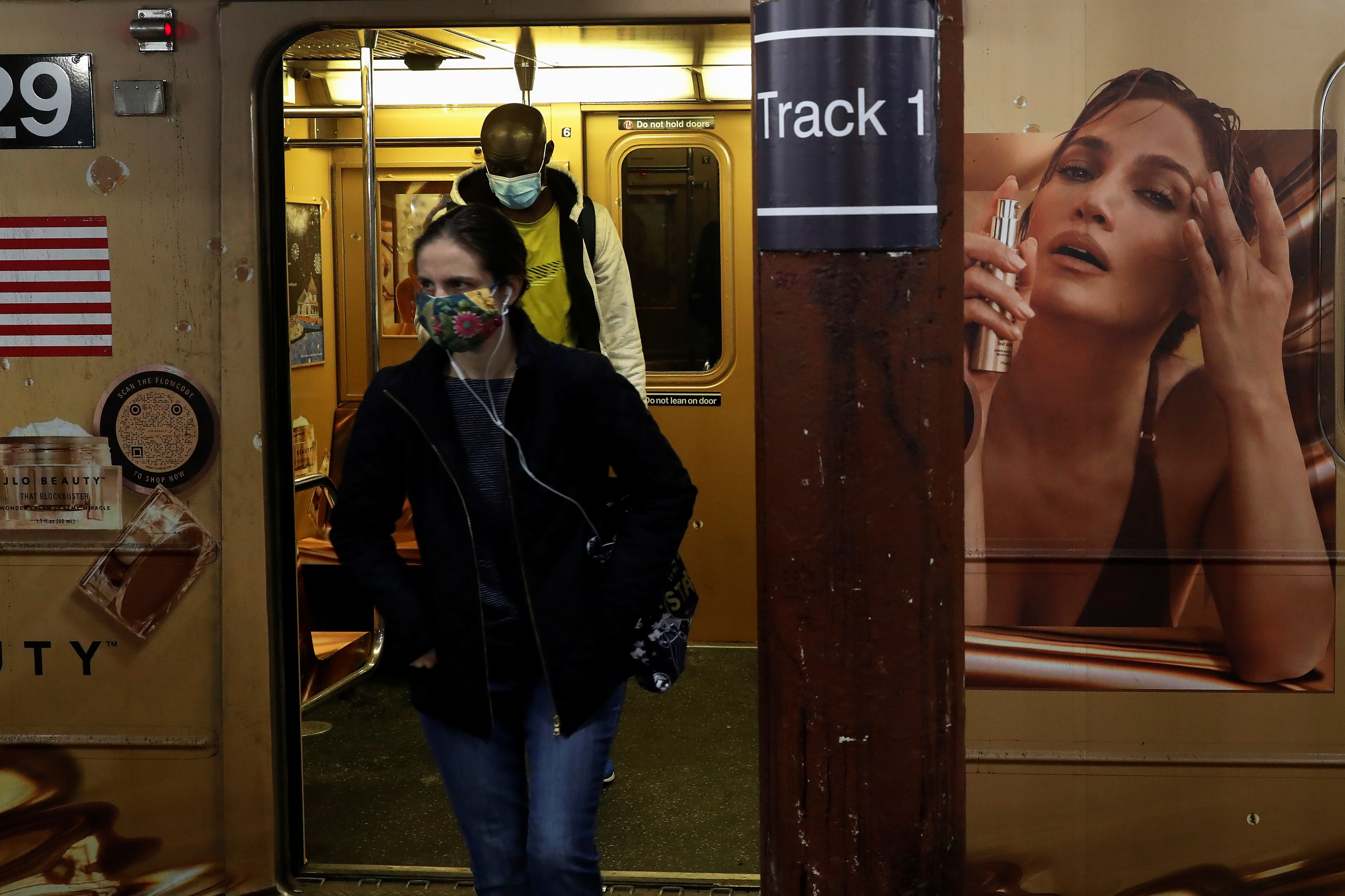 Subway riders wearing protective face masks exit the shuttle train during the coronavirus pandemic at the Times Square stop in New York City